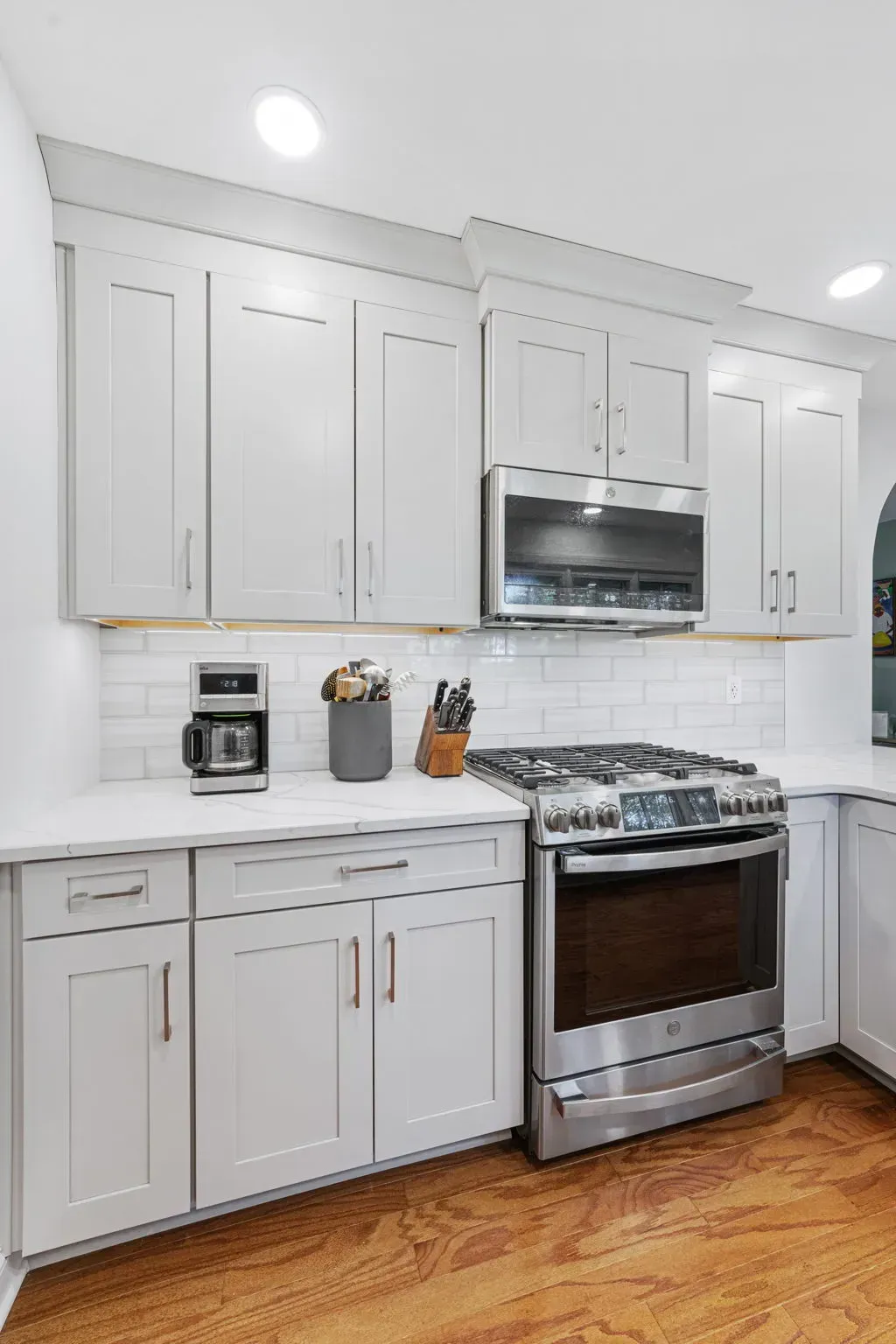 Bright white kitchen with cabinets, stainless steel stove and microwave, and hardwood floor  in Bucks County PA