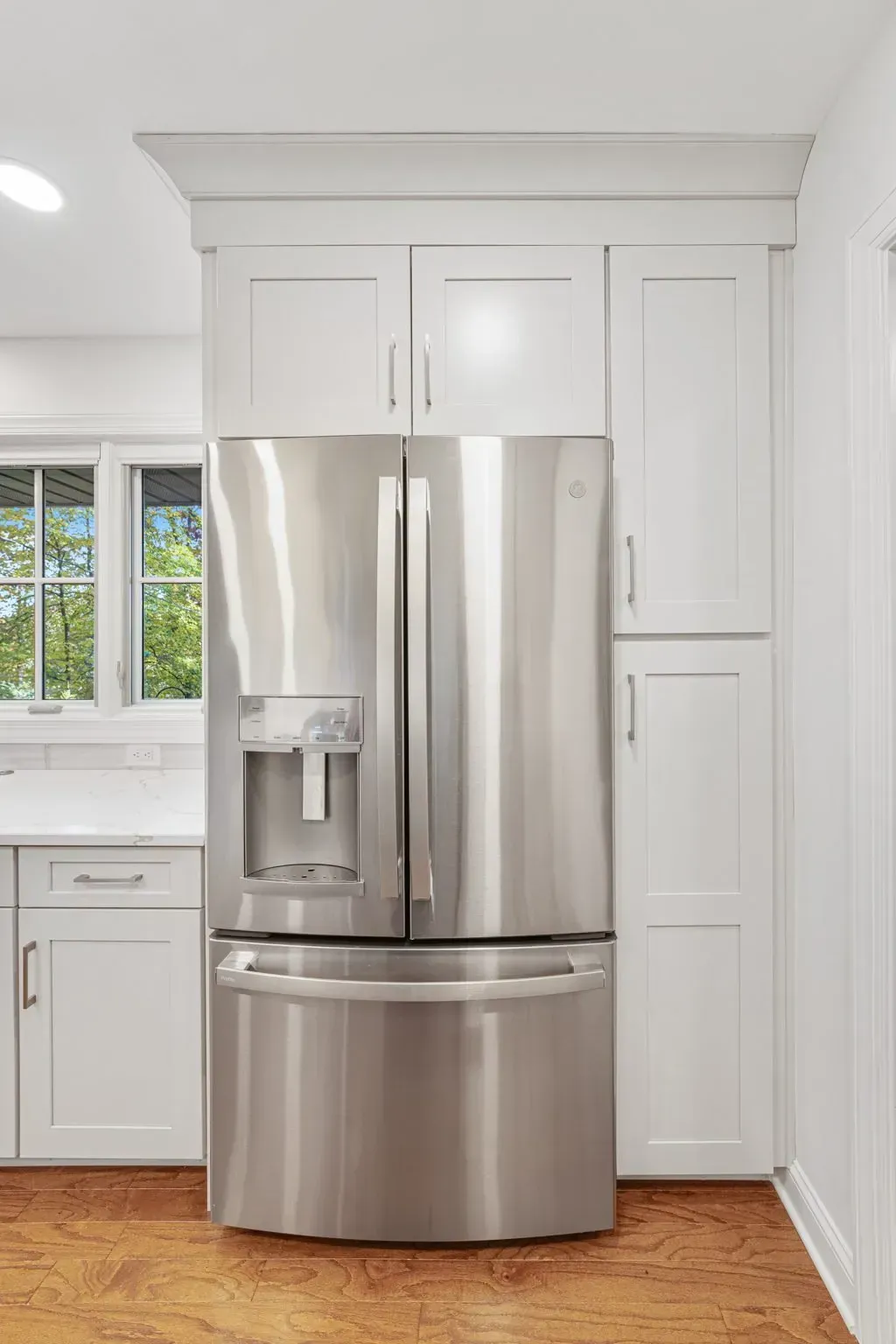 White kitchen with stainless steel French-door refrigerator and light wood floor in Bucks County PA