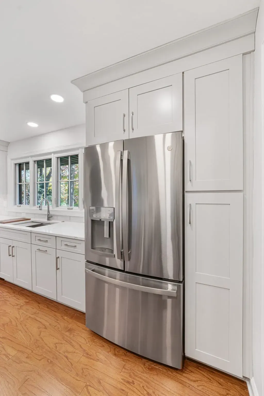 Bright white kitchen with stainless steel refrigerator, cabinets, and wood floor  in Bucks County PA