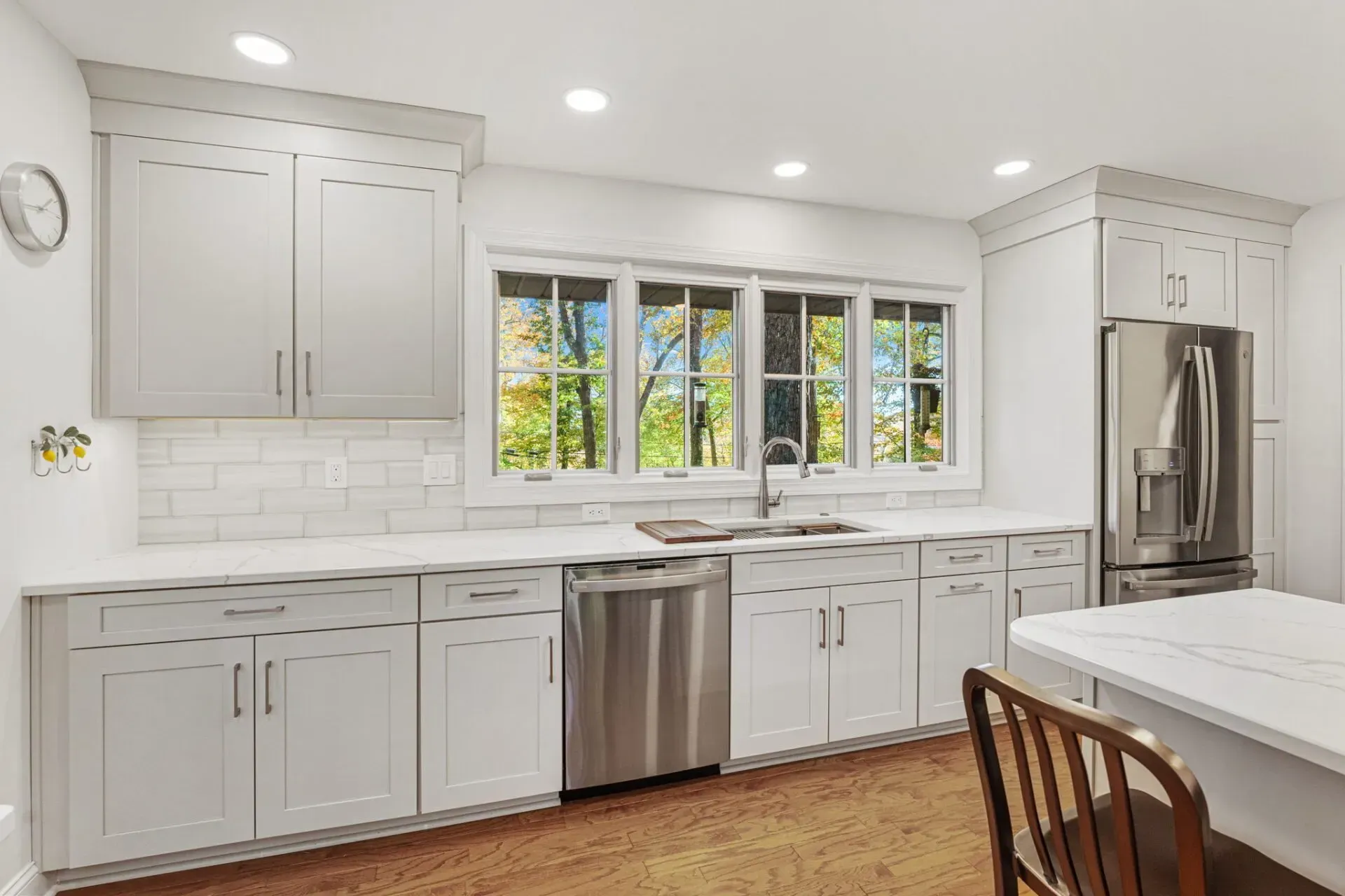 Bright kitchen with white cabinets, stainless steel appliances, large window, and marble island in Bucks County PA