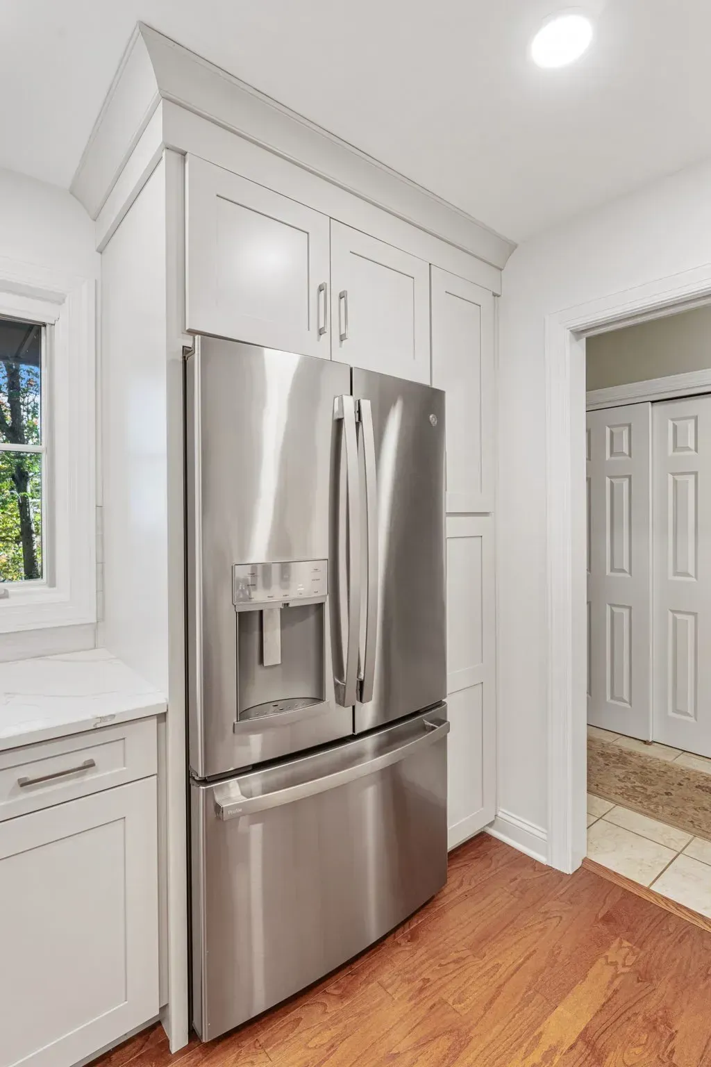Stainless steel French-door refrigerator in a bright white kitchen with wood floors in Bucks County PA