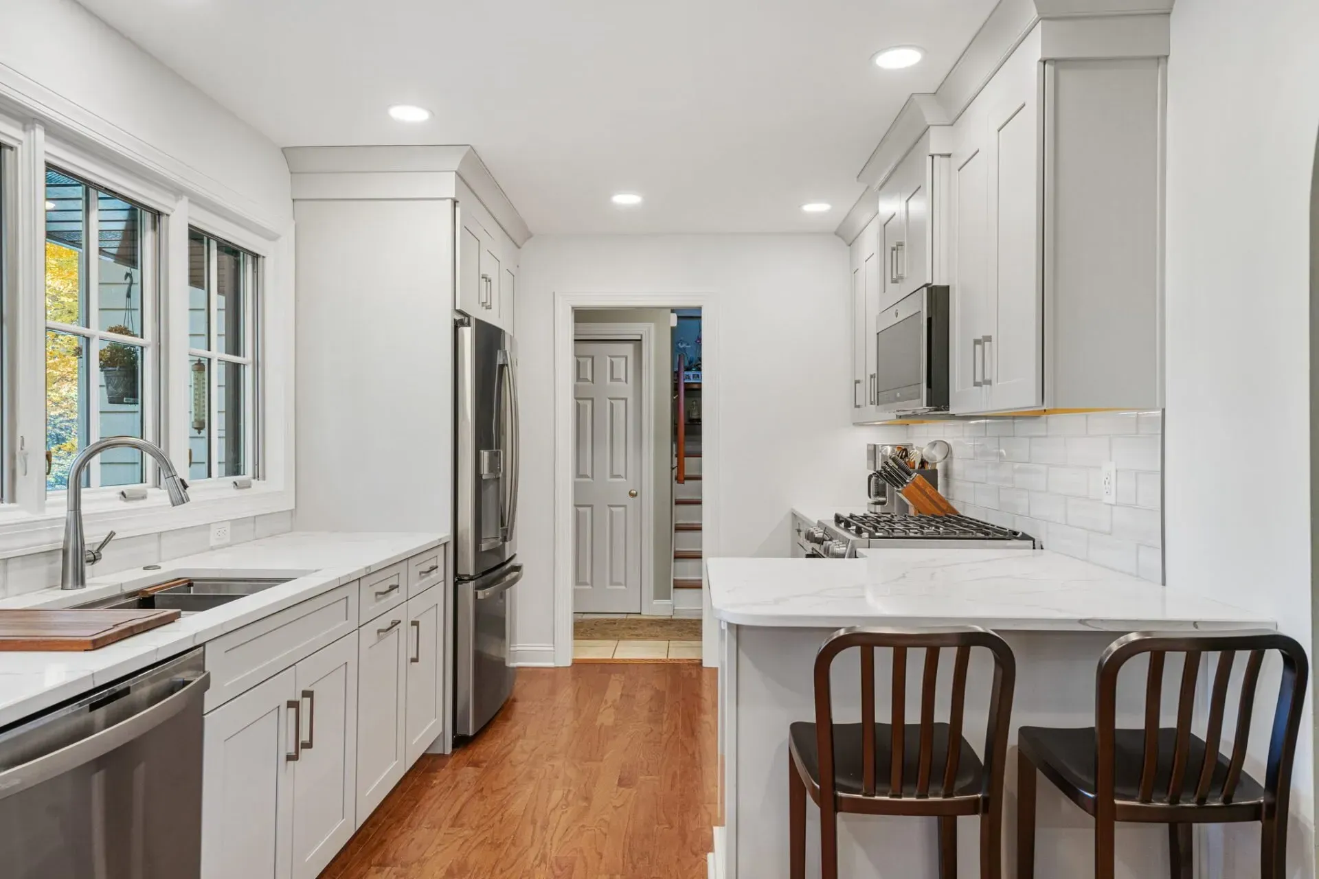 Bright white kitchen with stainless appliances, island seating, and hardwood floors in Bucks County PA