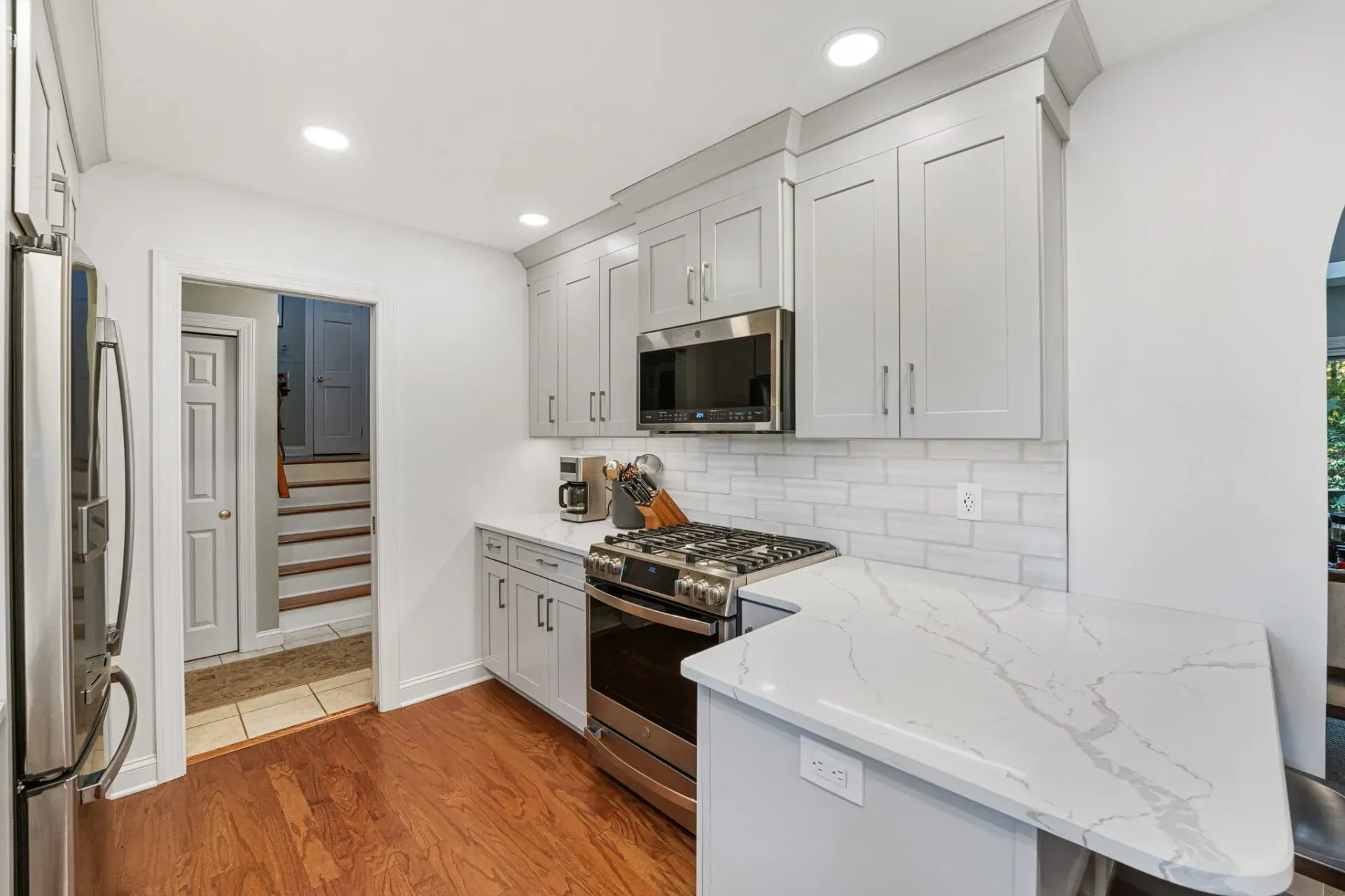 Bright white kitchen with stainless appliances, marble counters, and wood floors in Bucks County PA 