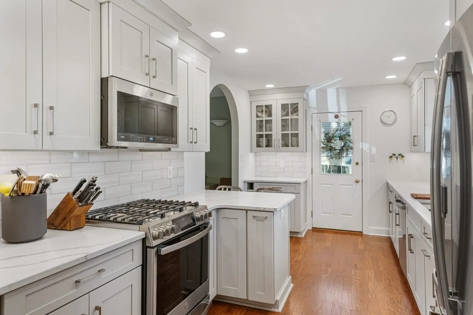 Bright white kitchen with stainless appliances, wood floors, and a small island in Bucks County PA