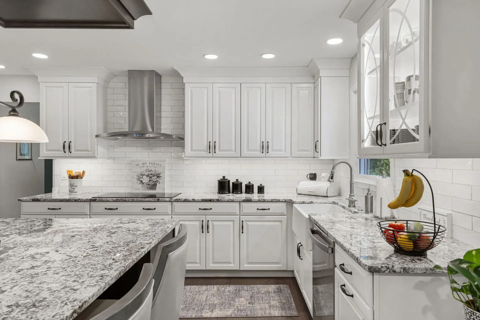 Bright white kitchen with marble countertops, stainless range hood, and fruit bowl on the counter In Bucks County PA