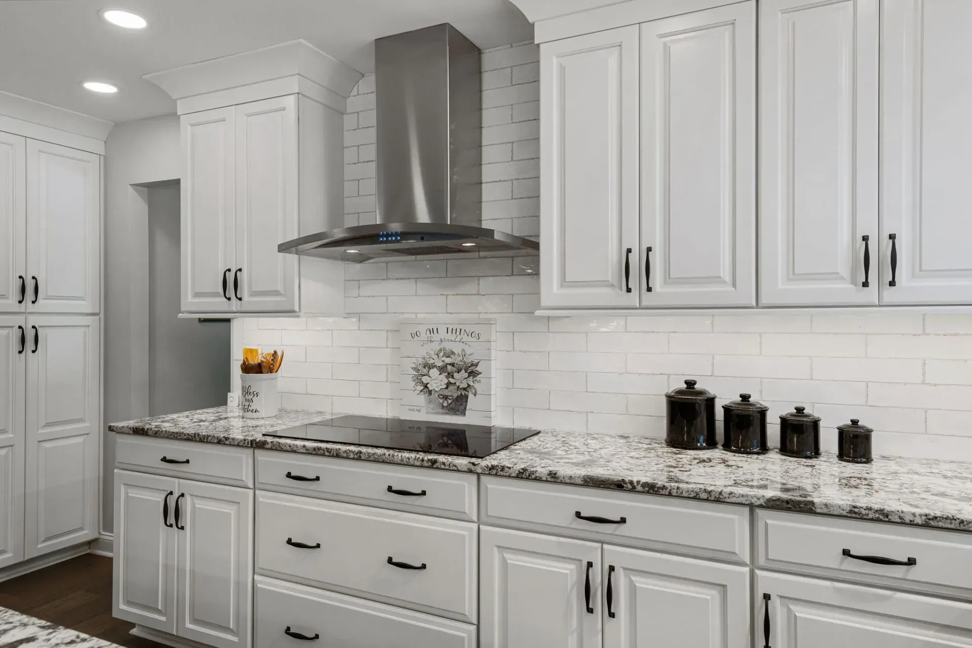 Bright white kitchen with shaker cabinets, granite countertops, and stainless steel range hood In Bucks County PA