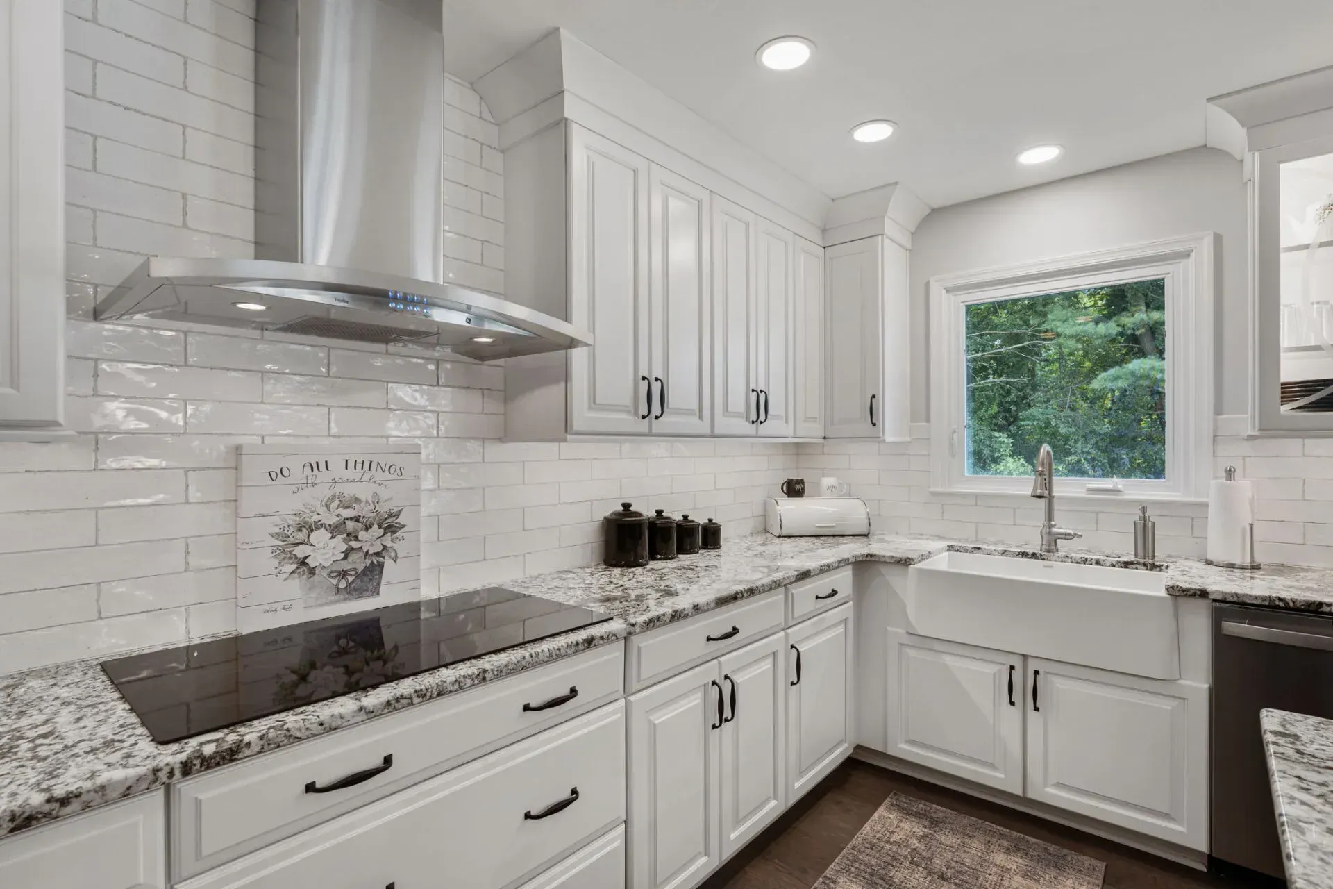 Bright white kitchen with granite counters, stainless range hood, and a window over the sink In Bucks County PA