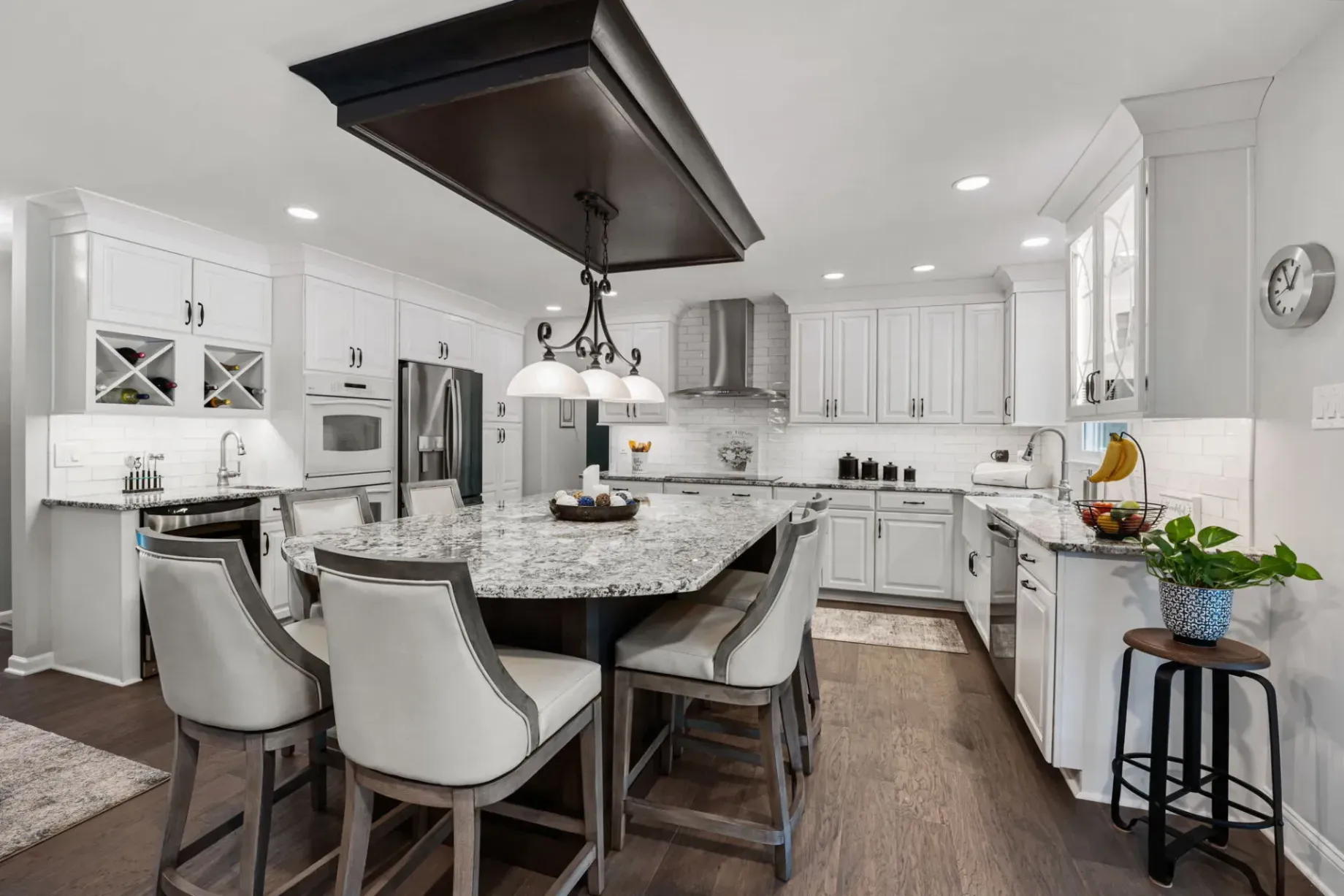 Bright modern kitchen with white cabinets, granite island, pendant lights, and barstools In Bucks County PA