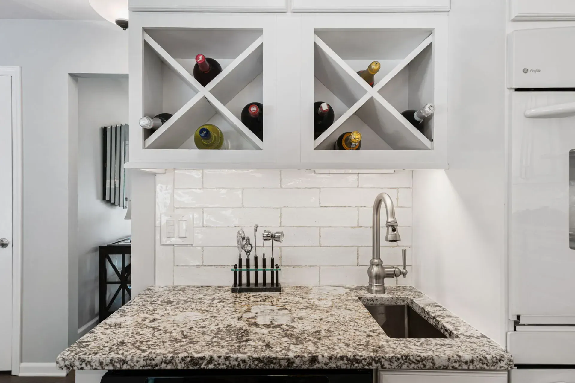 Modern kitchen with granite island, white cabinets, subway tile backsplash, and wine storage cabinets In Bucks County PA