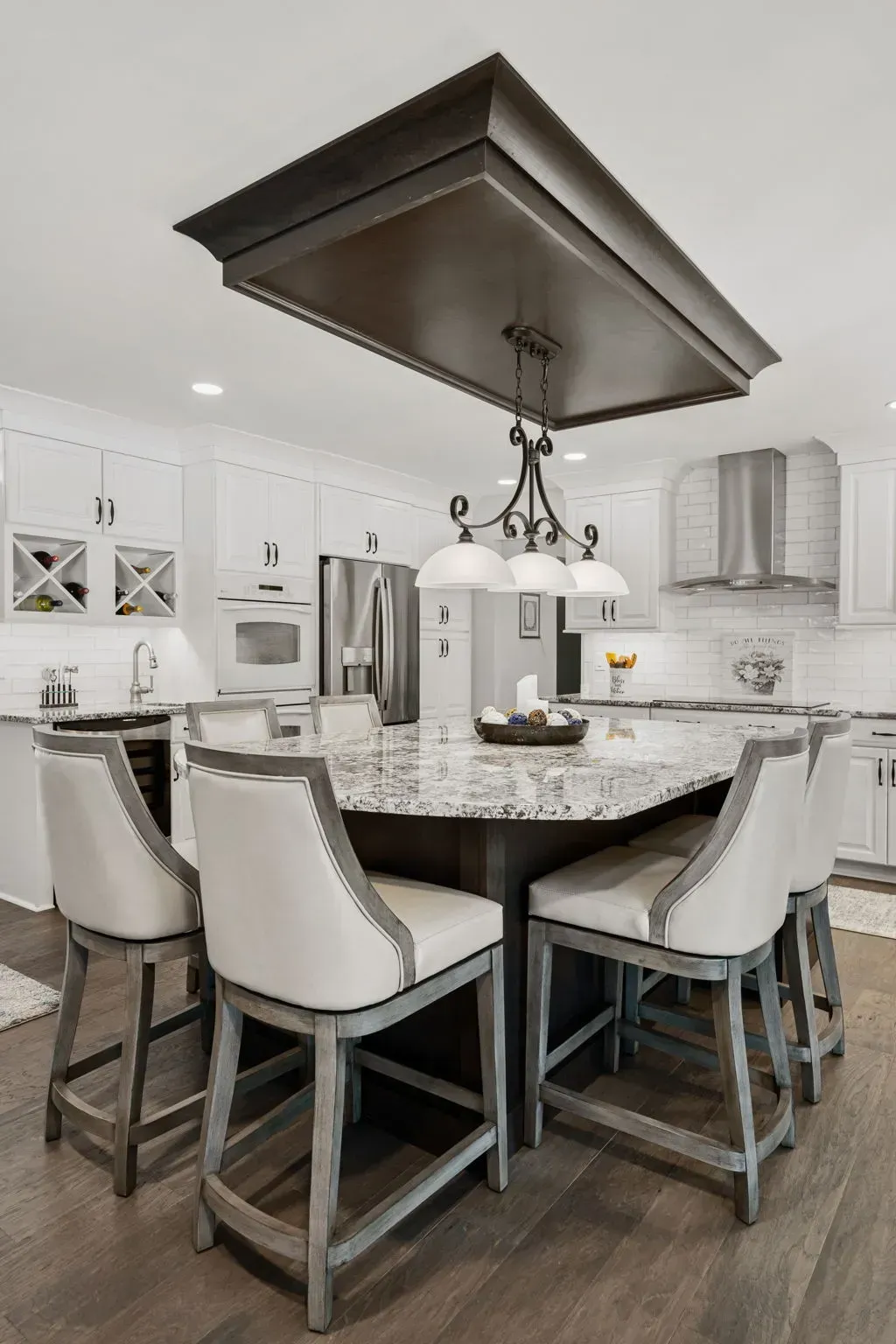 Modern kitchen island with granite countertop, white cabinets, and four upholstered bar stools In Bucks County PA