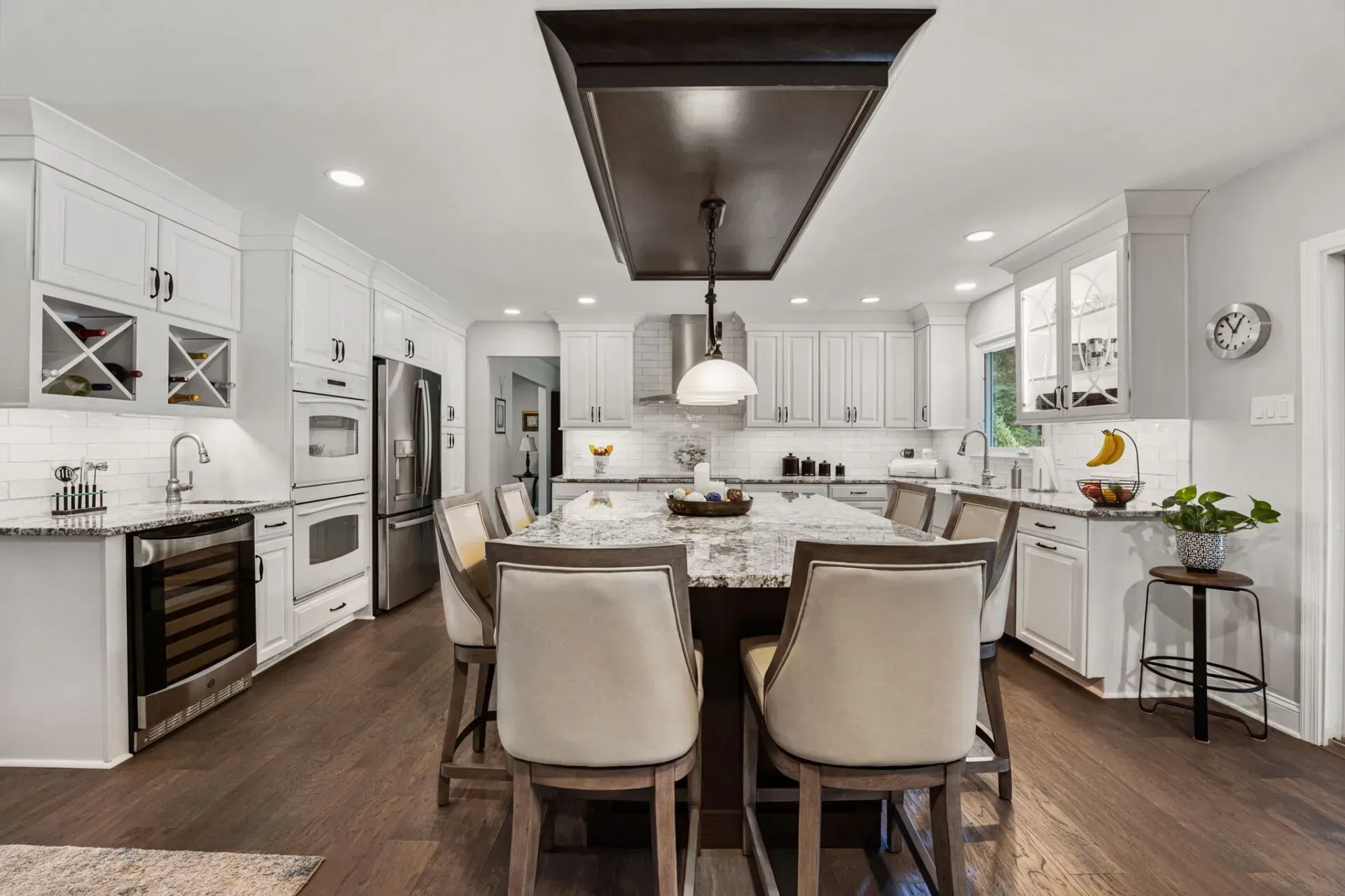 Bright modern kitchen with white cabinets, island seating, and dark wood floors In Bucks County PA