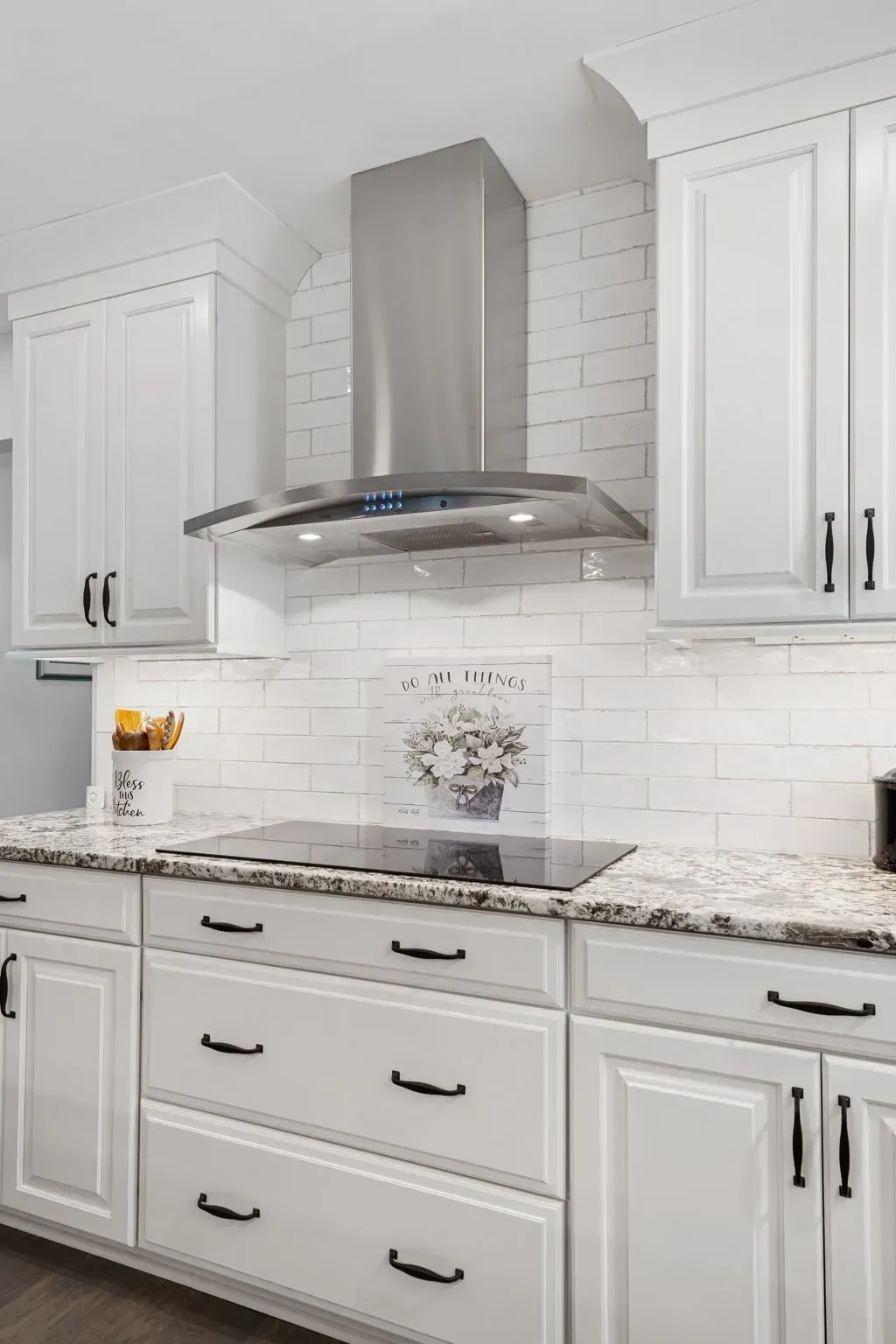 Bright white kitchen with granite countertops, subway tile backsplash, and a stainless steel range hood In Bucks County PA