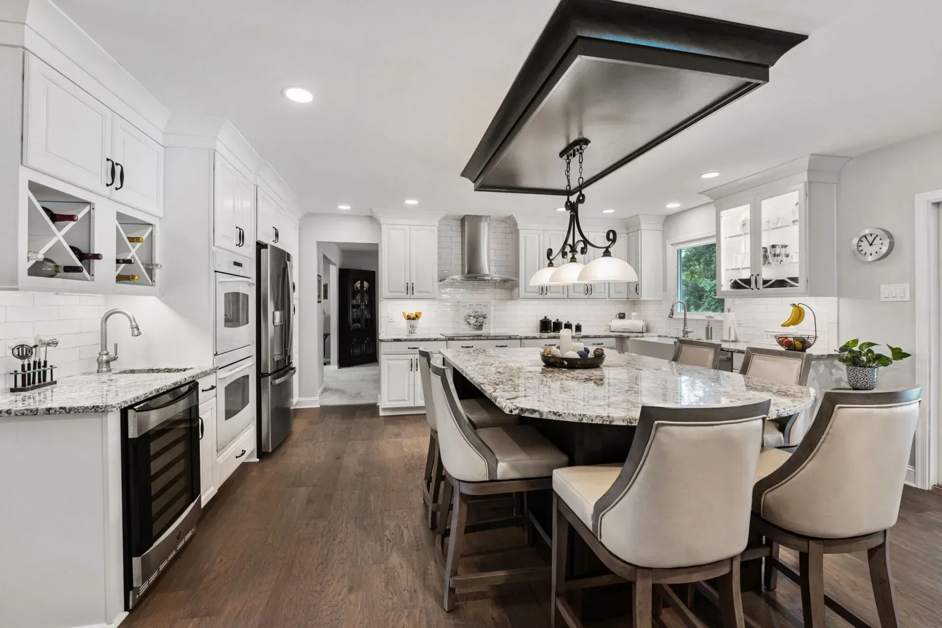 Bright modern kitchen with white cabinets, dark island, granite counters, and pendant lighting In Bucks County PA