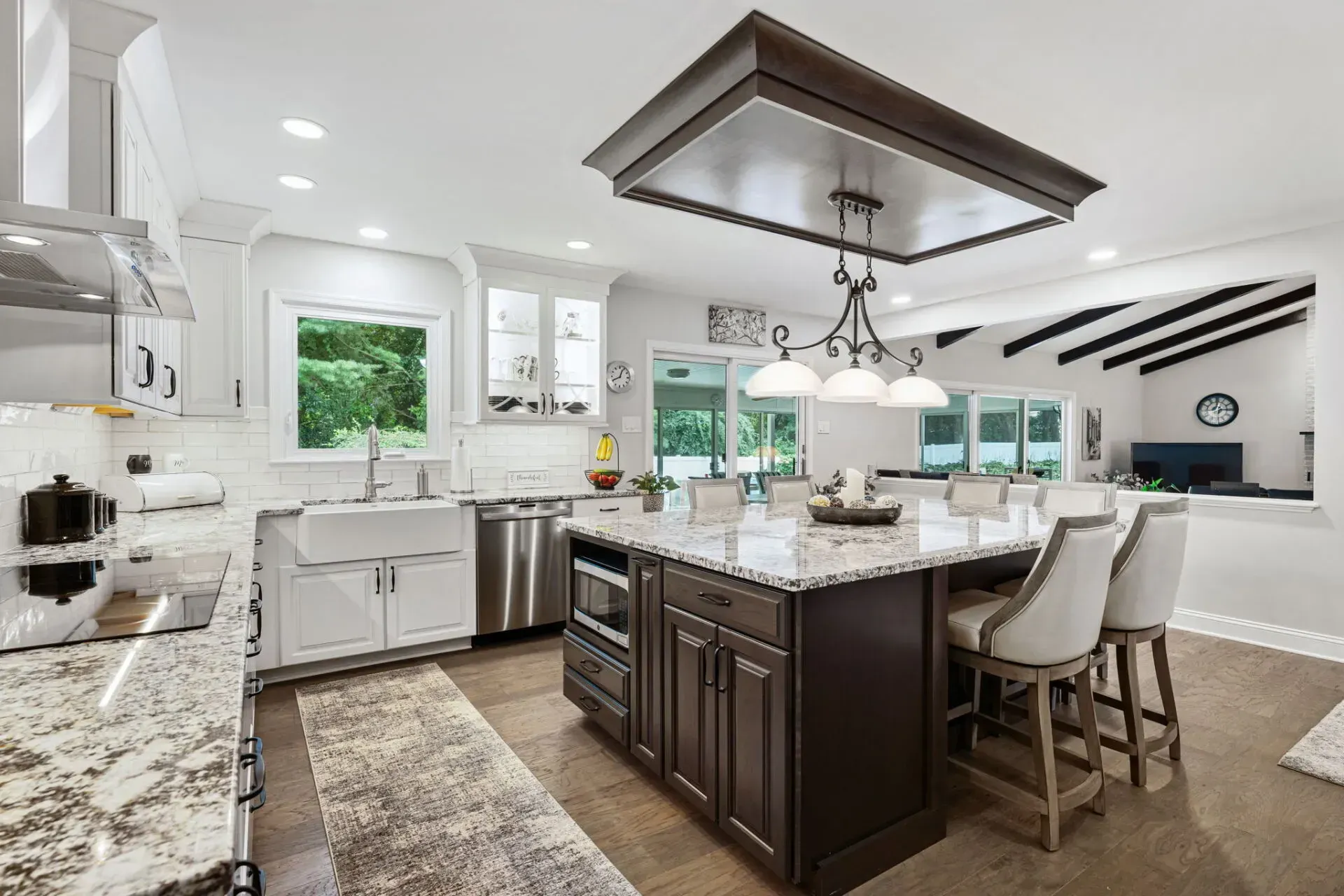 Bright modern kitchen with white cabinets, dark island, granite counters, and pendant lights In Bucks County PA