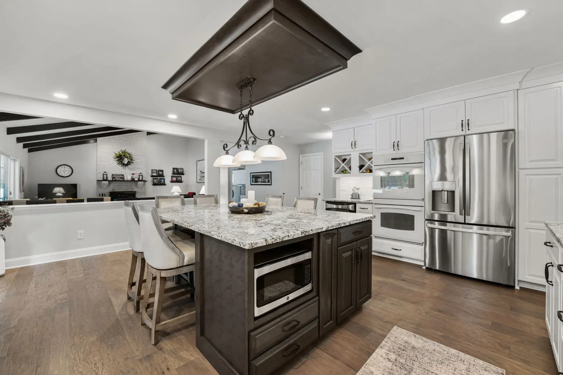 Modern kitchen with granite island, white cabinets, stainless steel appliances, and wood flooring In Bucks County PA