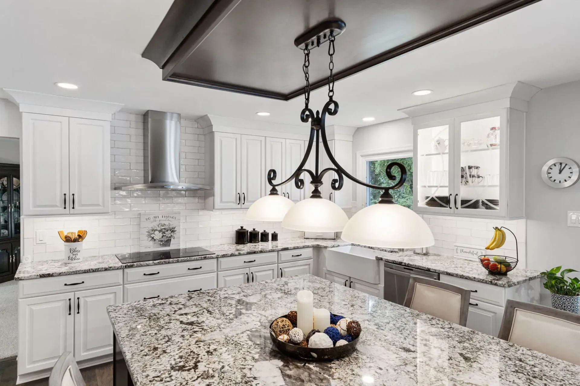 Bright modern kitchen with white cabinets, granite island, stainless steel appliances, and pendant lights In Bucks County PA