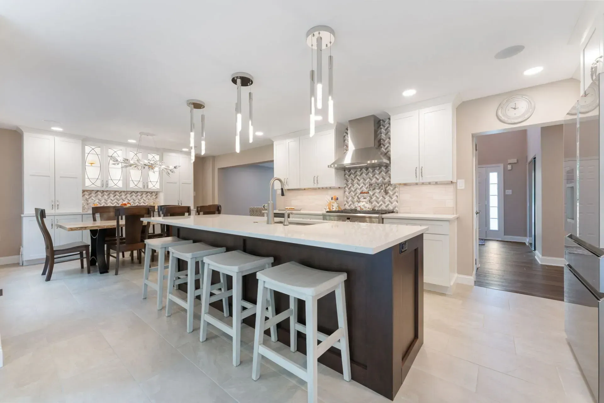Modern white kitchen with island, bar stools, pendant lights, and open dining area In Bucks County PA