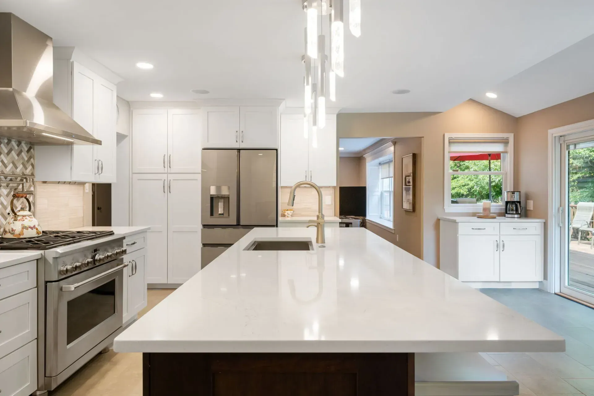 Modern white kitchen with large island, stainless steel appliances, and pendant lights In Bucks County PA