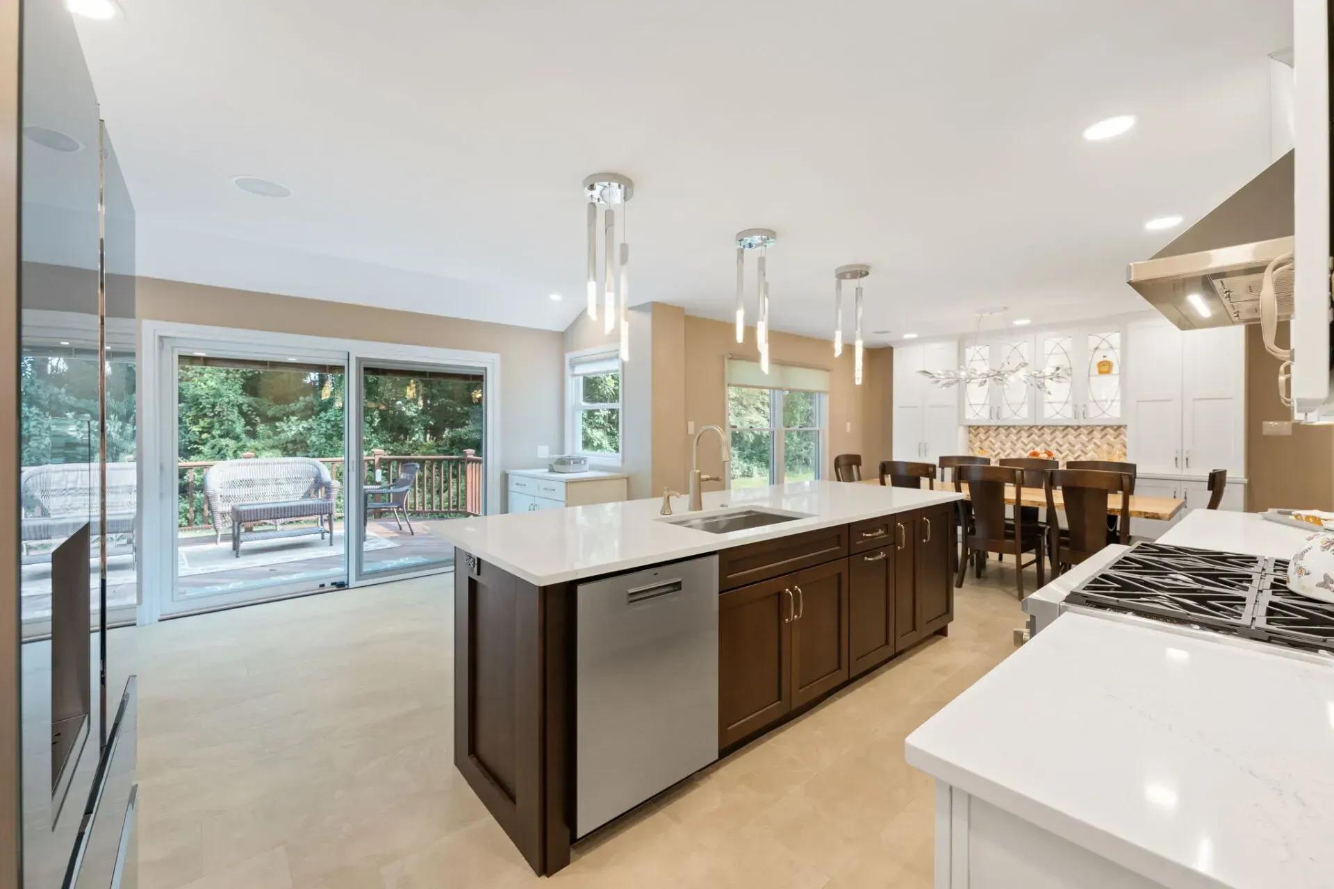 Modern kitchen with a large island, dark wood cabinets, white countertops, and sliding glass doors to a patio In Bucks County PA