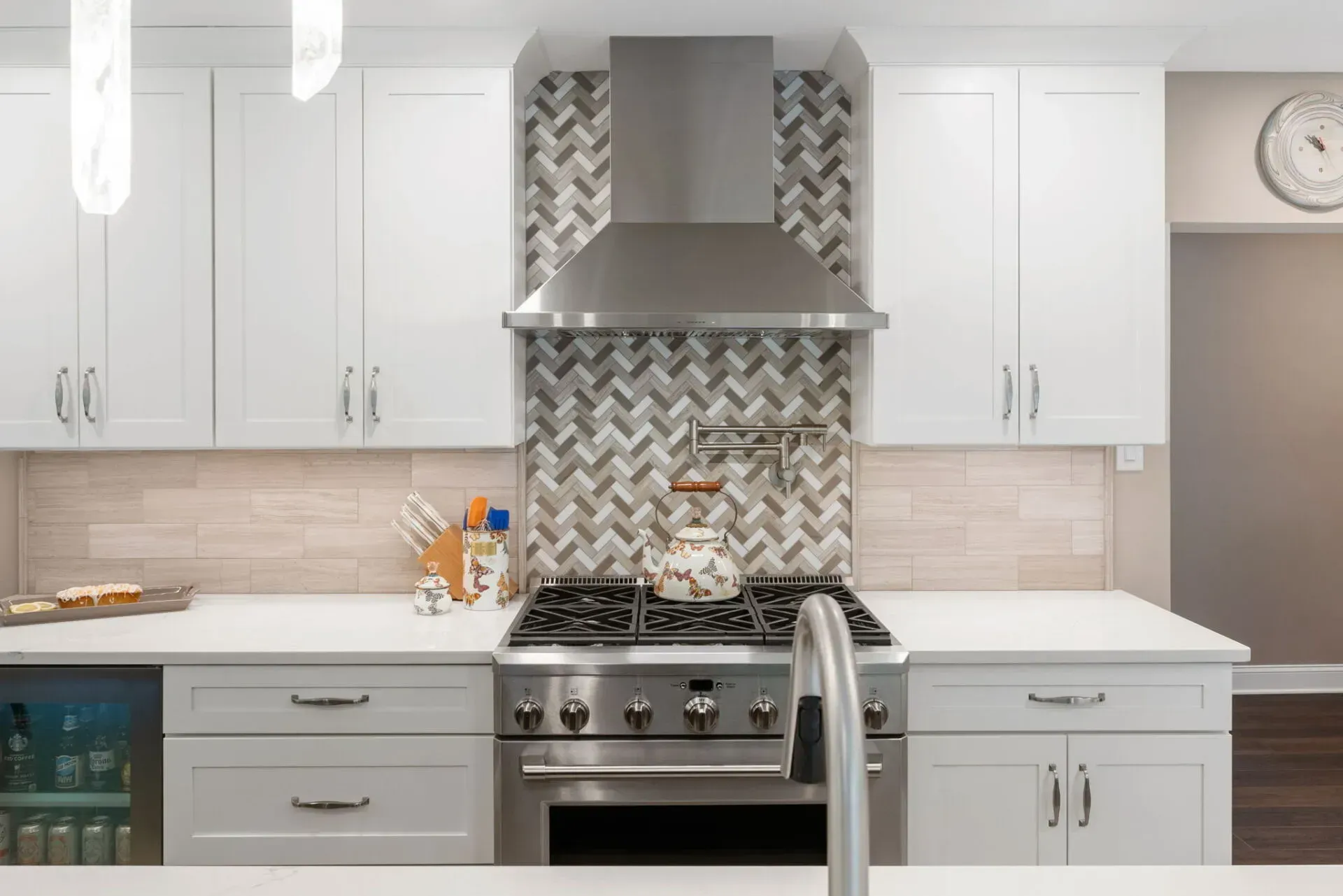 Modern white kitchen with stainless steel range hood and herringbone tile backsplash In Bucks County PA