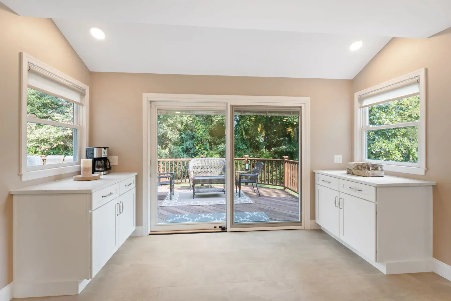 Bright kitchen with white cabinets and sliding glass doors opening to a patio and trees outdoors In Bucks County PA