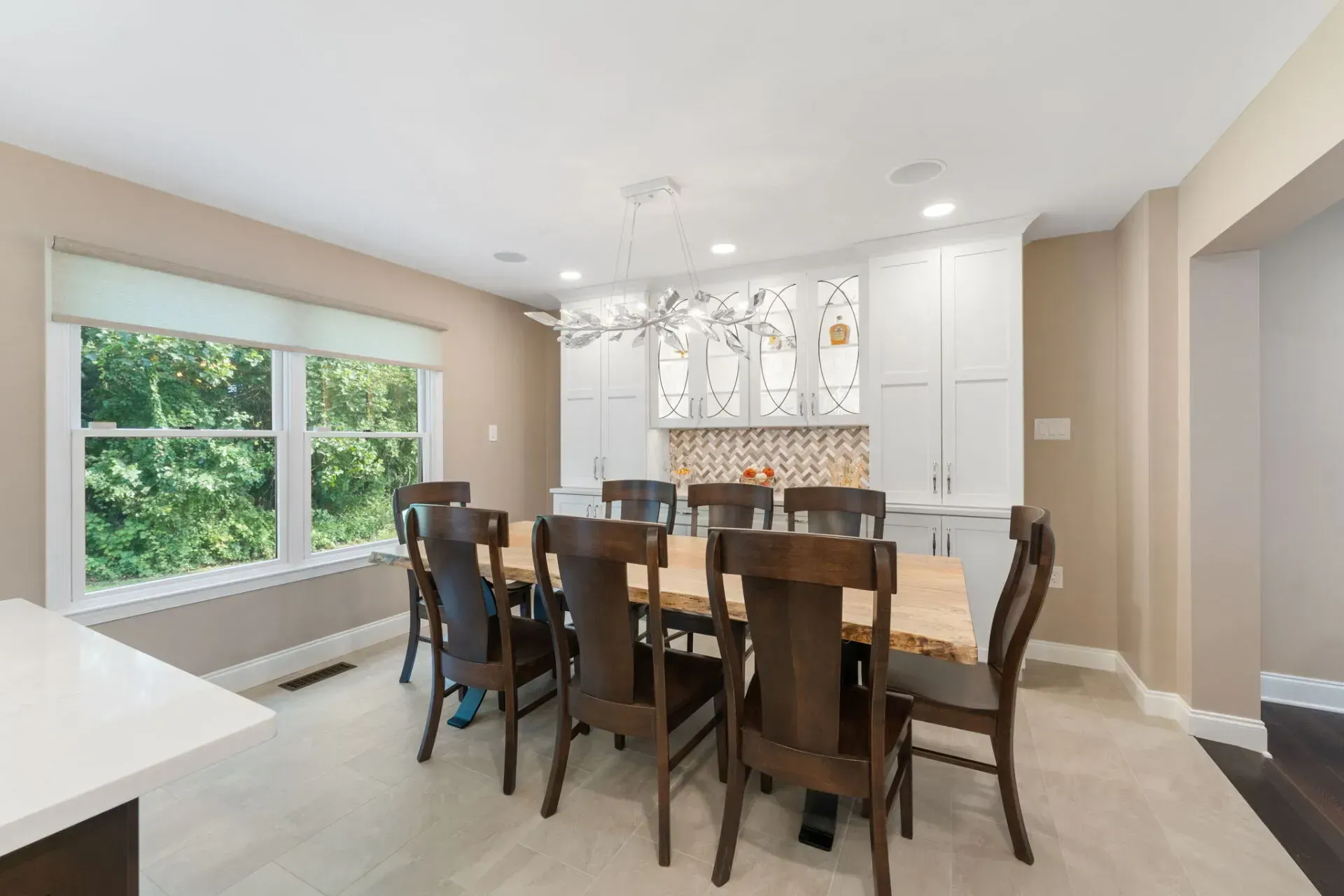 Bright modern dining room with wooden table, chairs, large windows, and kitchen island In Bucks County PA