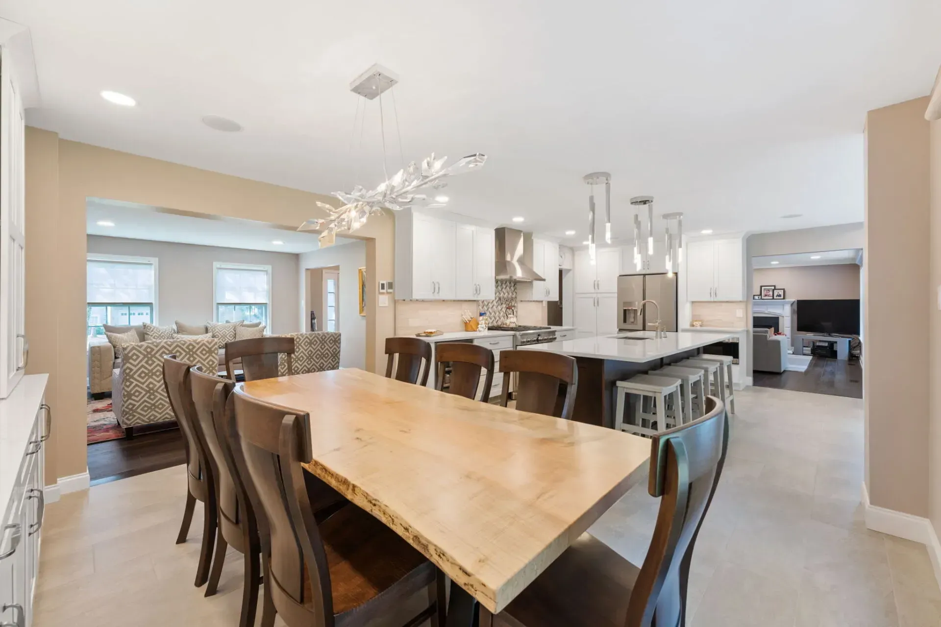 Open-concept dining and kitchen area with a wooden table, dark chairs, and a bright island countertop In Bucks County PA
