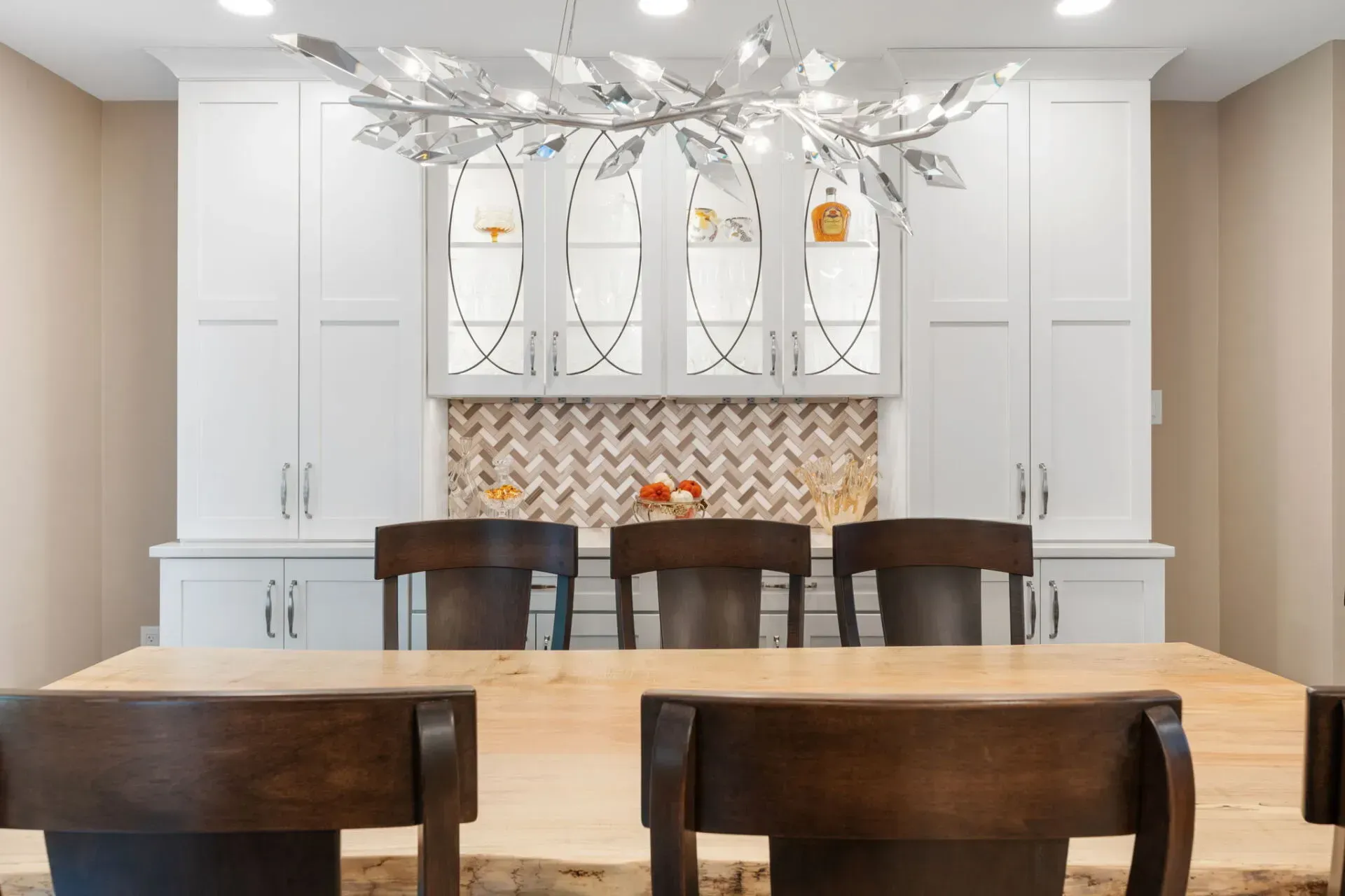 Bright dining room with a long wooden table, dark chairs, white cabinets, and a chandelier In Bucks County PA