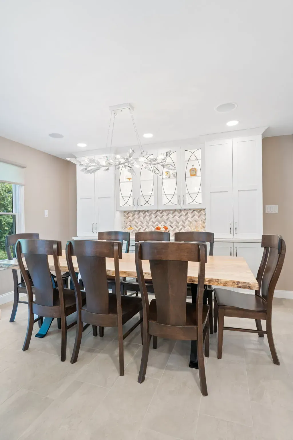 Bright dining room with a dark wood table, chairs, white cabinetry, and a chandelier In Bucks County PA