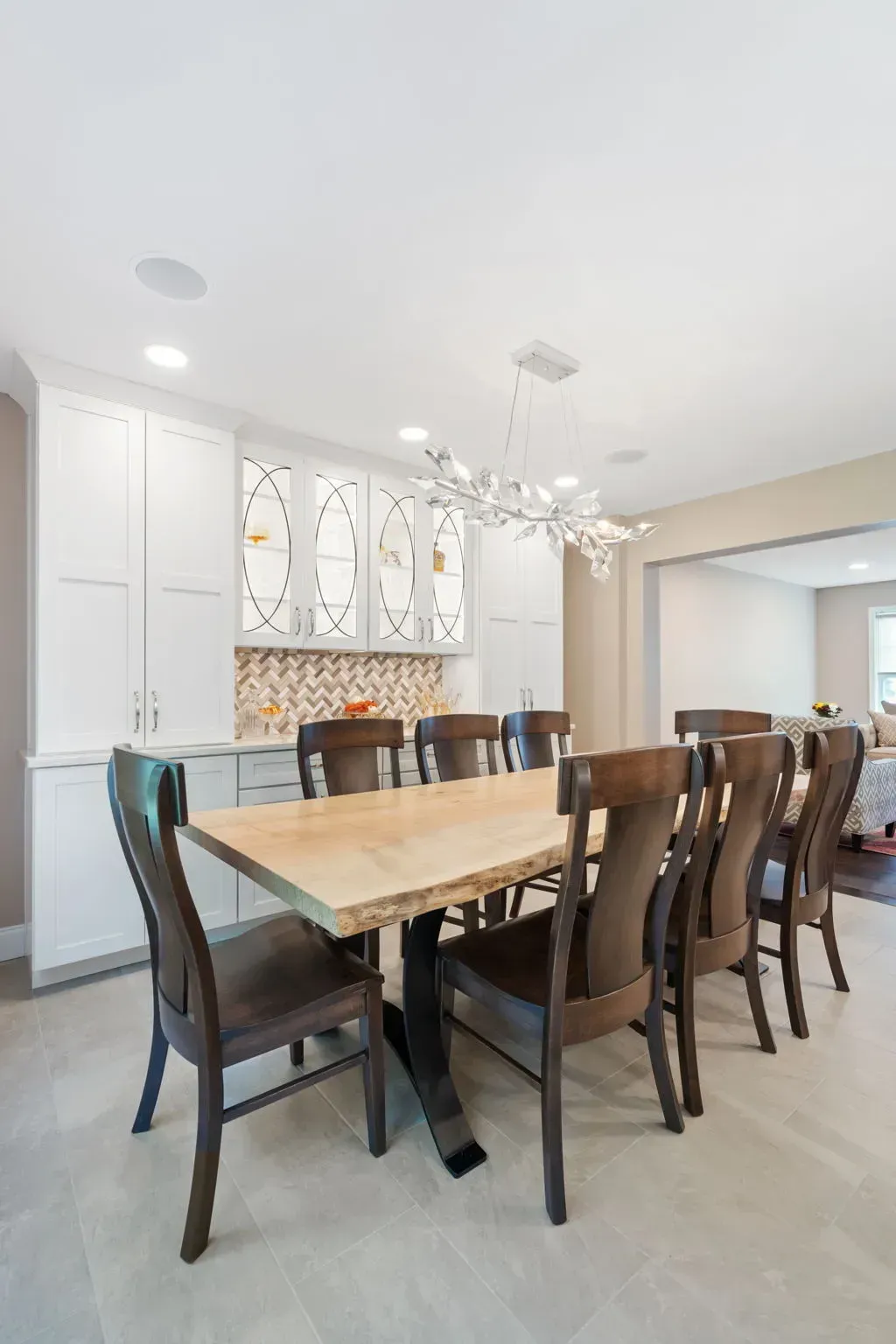Bright dining room with a wooden table, dark chairs, white cabinetry, and a modern chandelier In Bucks County PA