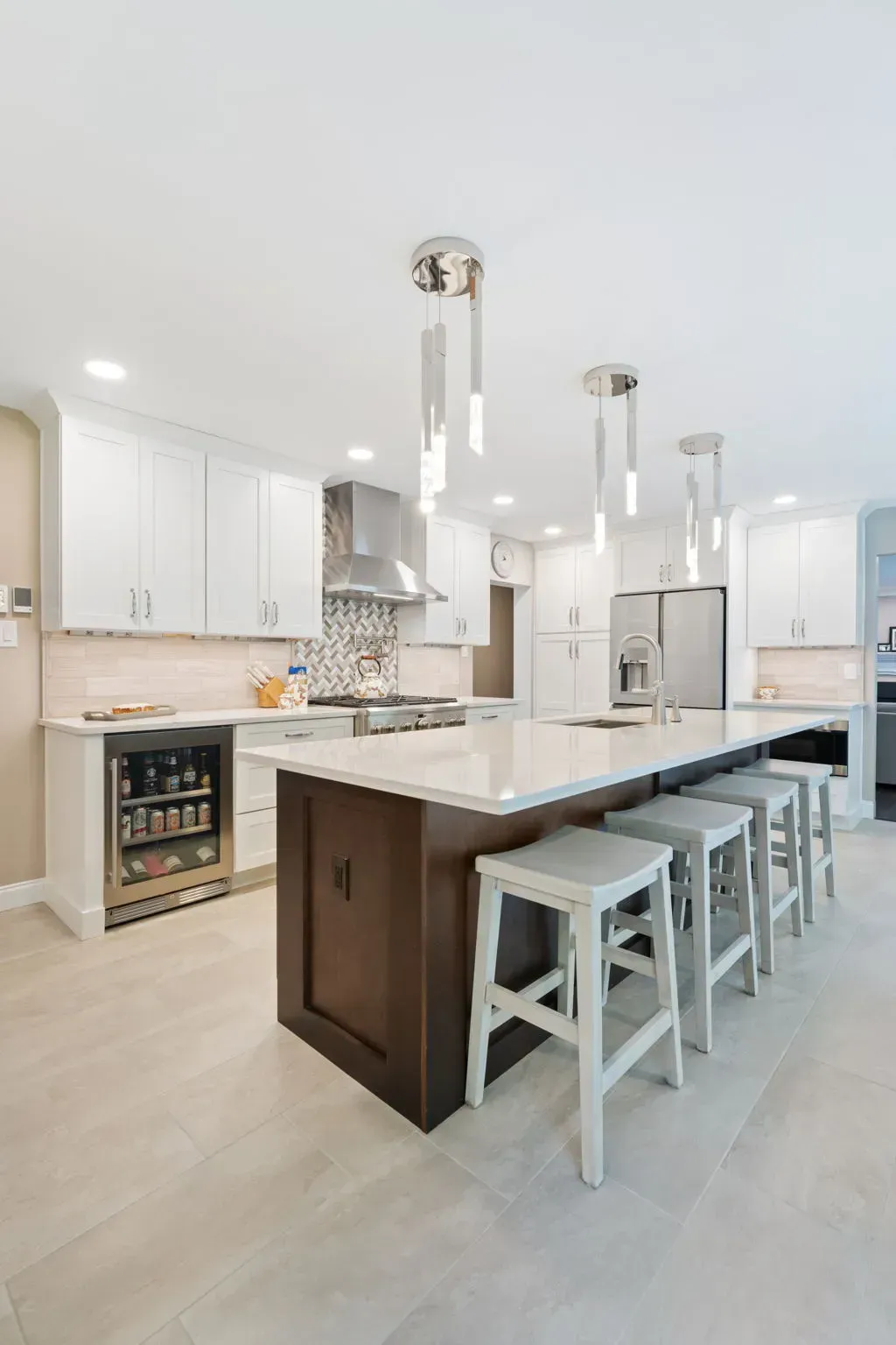 Bright modern kitchen with white cabinets, large island, pendant lights, and barstools In Bucks County PA