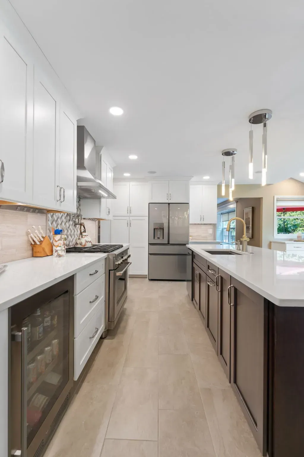 Modern bright kitchen with white cabinets, dark island, stainless appliances, and light wood floors In Bucks County PA
