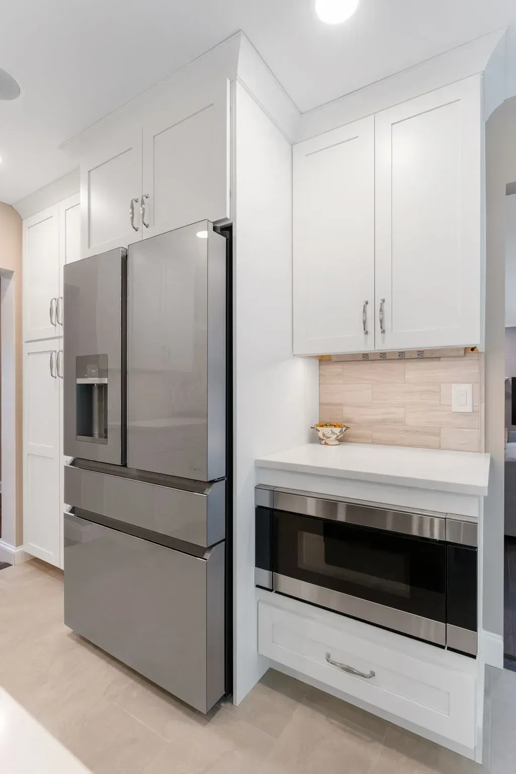 Modern white kitchen with stainless steel refrigerator and built-in oven under white cabinets In Bucks County PA