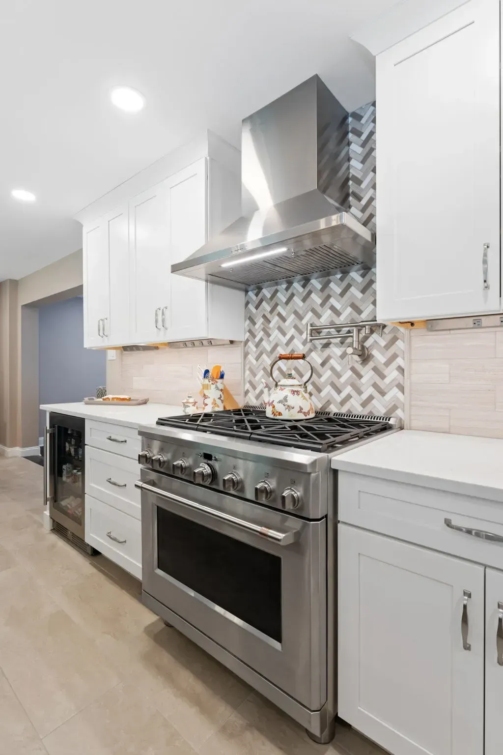 Bright modern kitchen with white cabinets, stainless steel stove, and patterned backsplash In Bucks County PA
