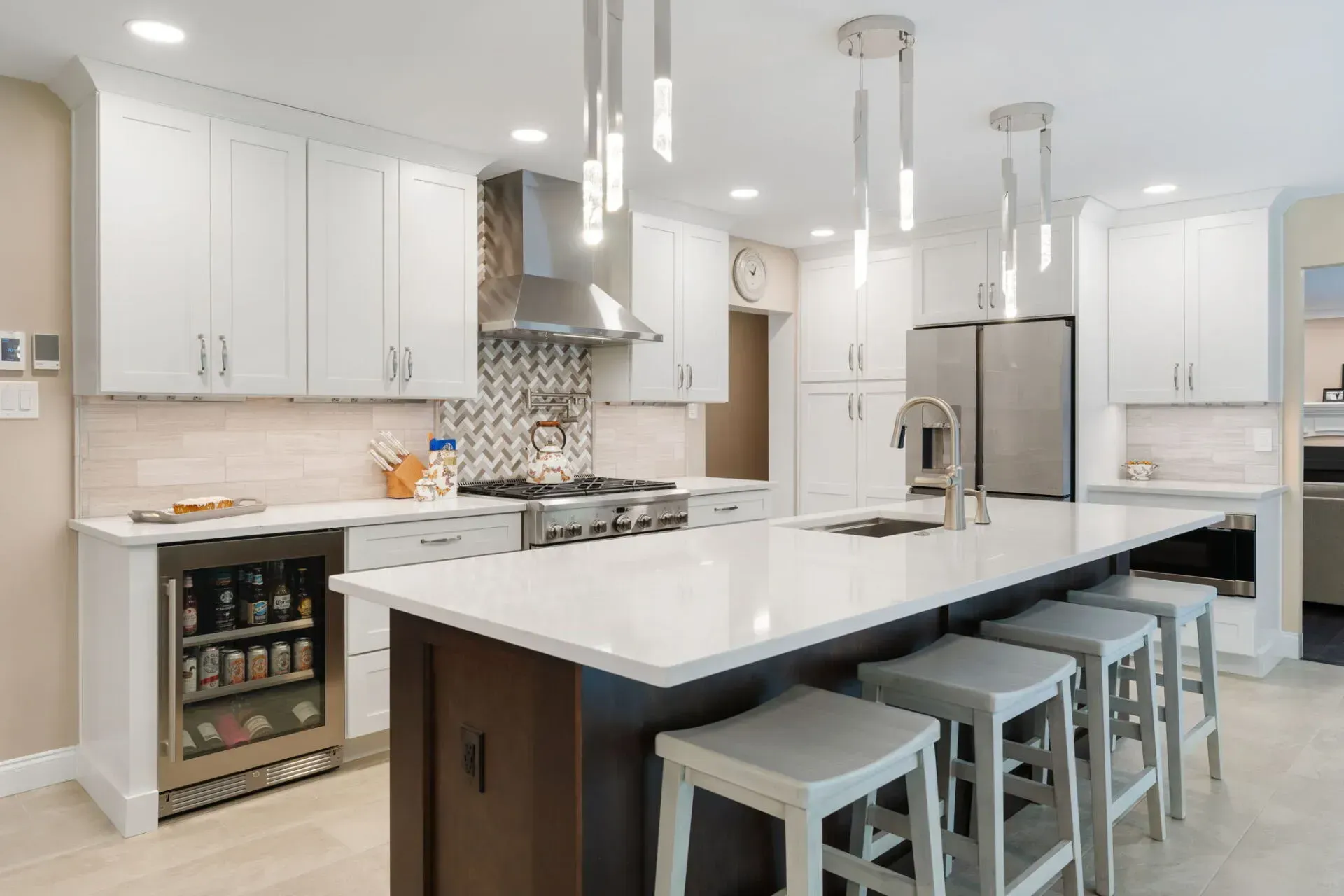 Bright modern kitchen with white cabinets, large island, bar stools, and stainless steel appliances In Bucks County PA