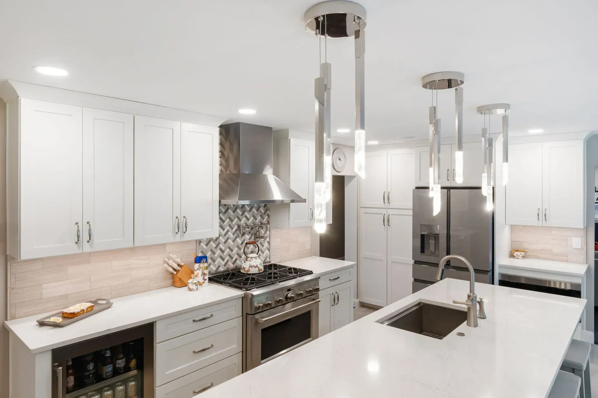Bright modern kitchen with white cabinets, island sink, stainless steel appliances, and pendant lights In Bucks County PA