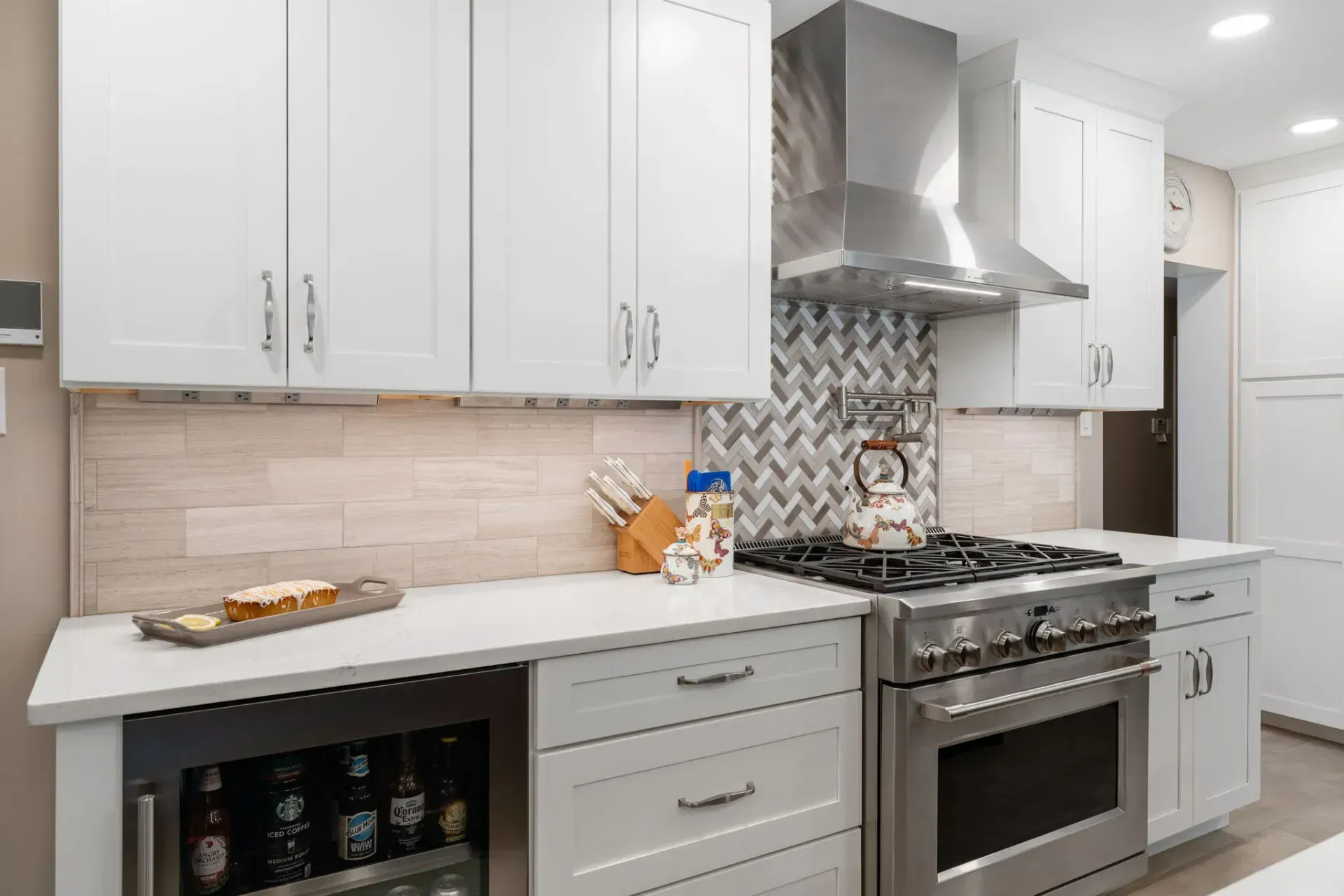 Modern white kitchen with stainless steel stove, patterned backsplash, and white cabinets In Bucks County PA