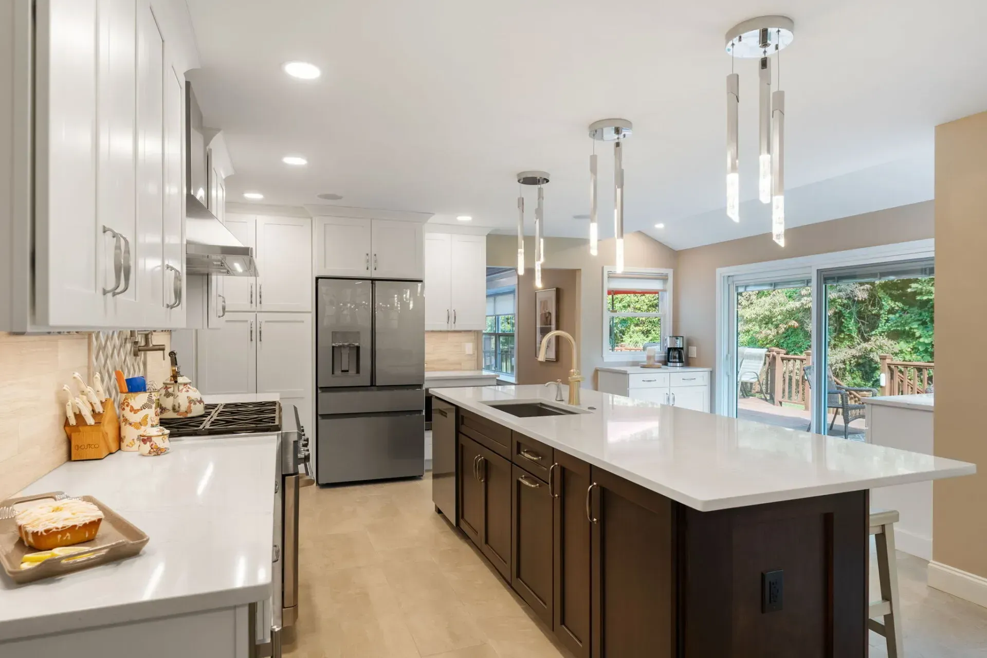 Bright modern kitchen with white cabinets, dark island, stainless fridge, and large windows In Bucks County PA