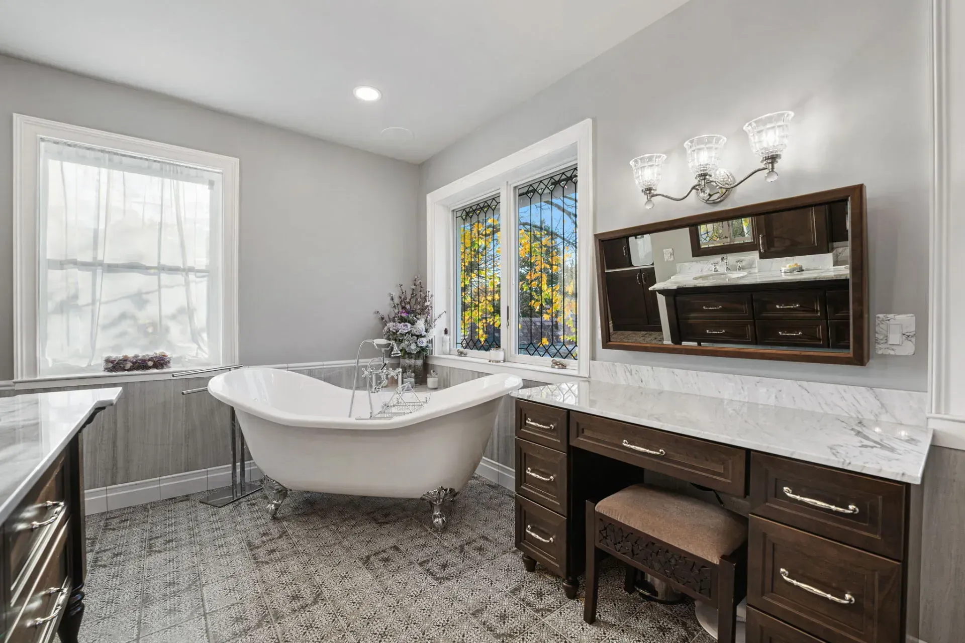 Bright bathroom with a freestanding tub, vanity, mirror cabinet, and patterned tile floor in Bucks County PA
