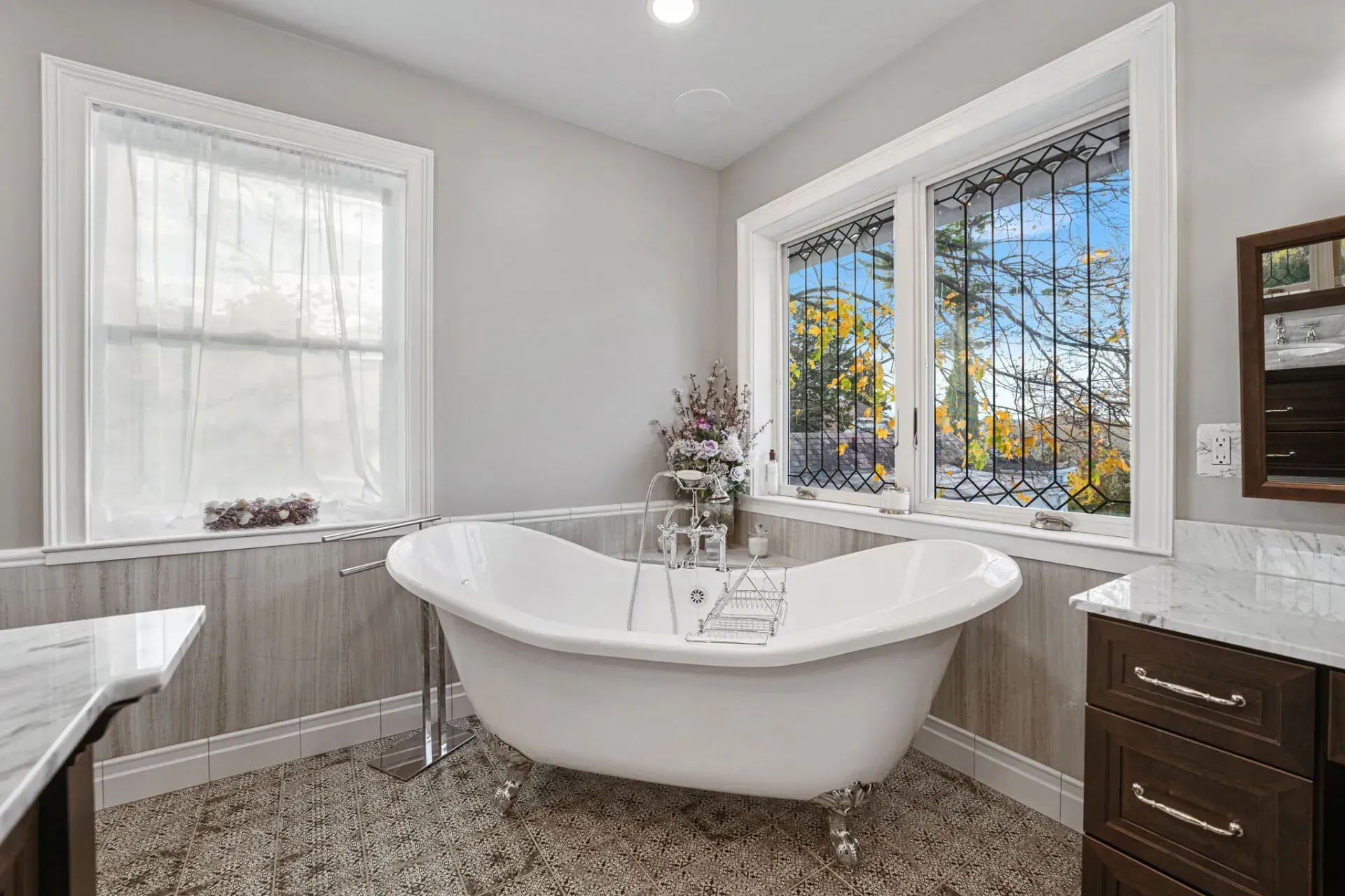 Bright bathroom with a white soaking tub, two windows, and dark wood cabinets in Bucks County PA