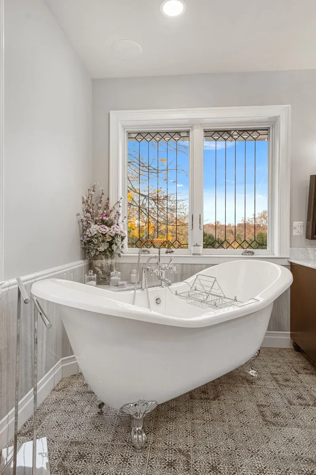 Bright bathroom with a white freestanding tub by a window overlooking trees and sky in Bucks County PA