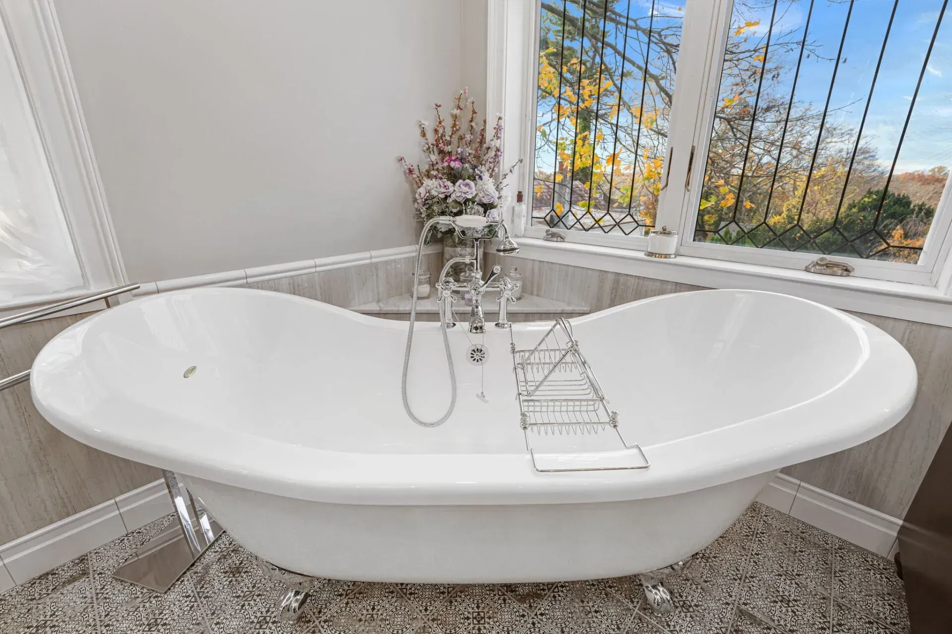 White freestanding bathtub beneath a window, with chrome faucet and bath caddy in a bright bathroom in Bucks County PA