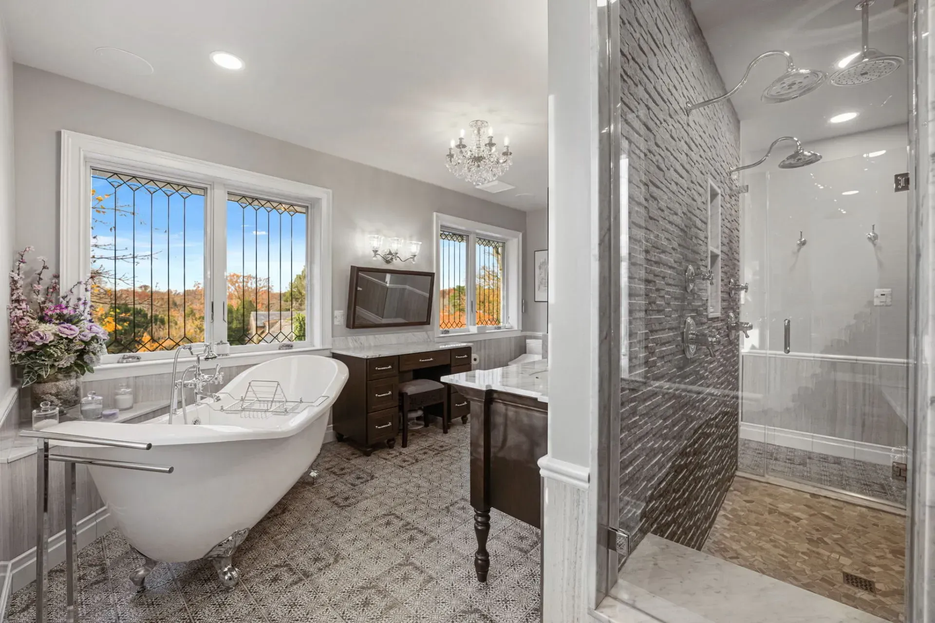Bright bathroom with freestanding tub, glass shower, vanity, and large windows overlooking greenery in Bucks County PA