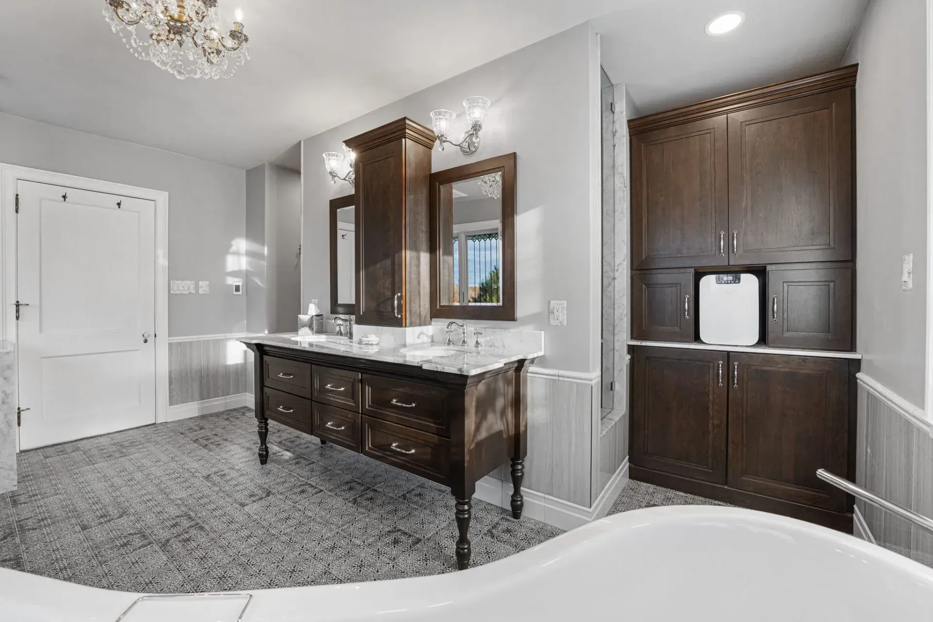 Elegant bathroom with dark wood vanity, marble countertop, large mirror, and built-in cabinet. in Bucks County PA
