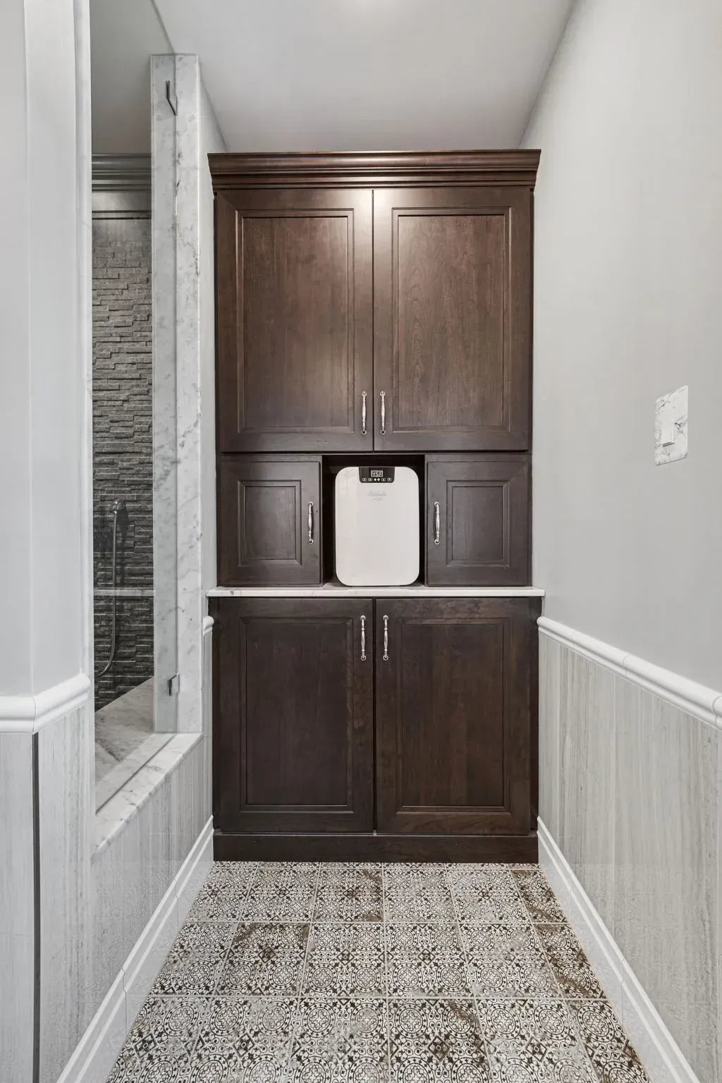 Built-in dark wood cabinet in a bathroom alcove beside a tiled shower in Bucks County PA