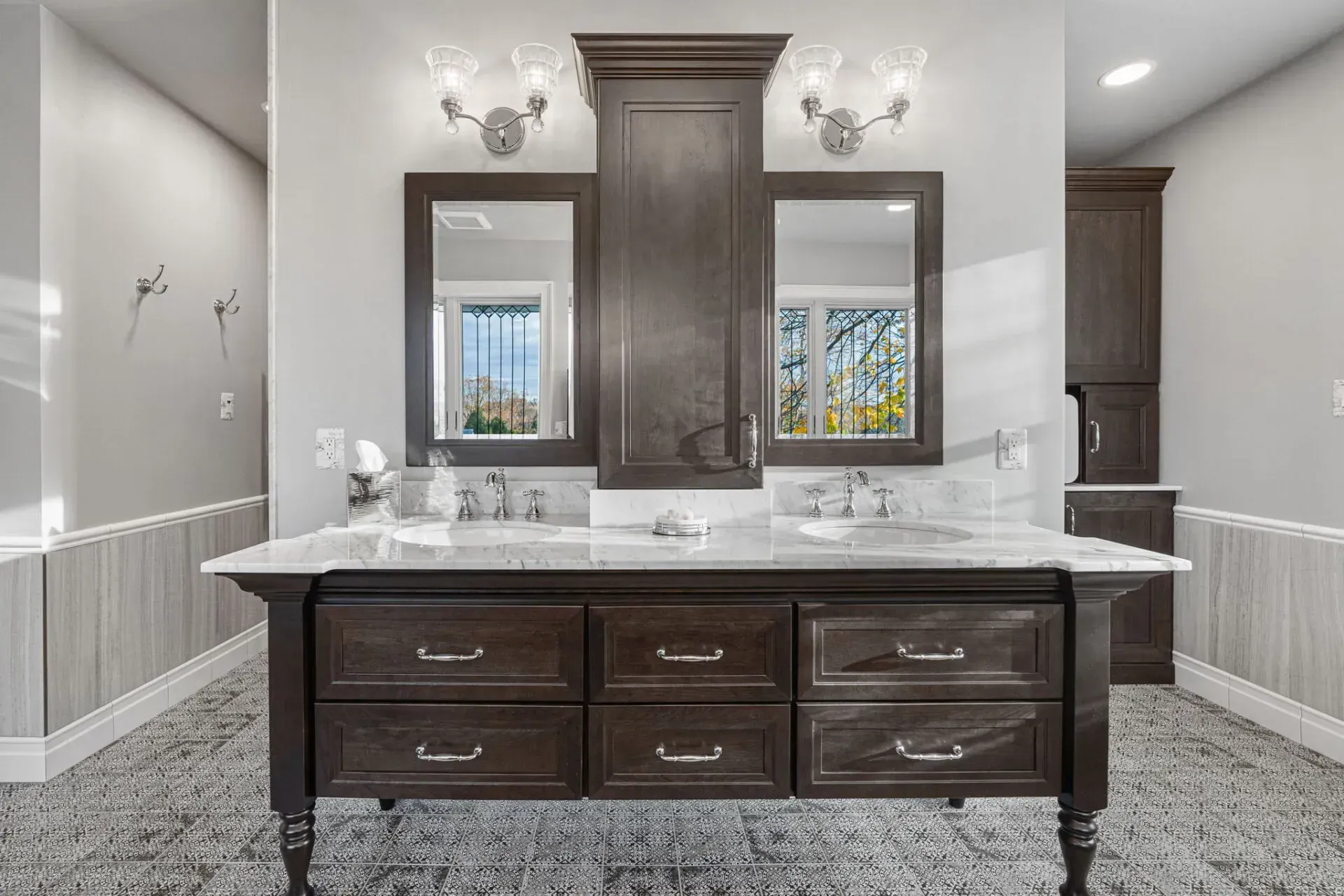 Elegant bathroom vanity with dark wood cabinets, marble countertop, and twin mirrors under wall sconces. in Bucks County PA