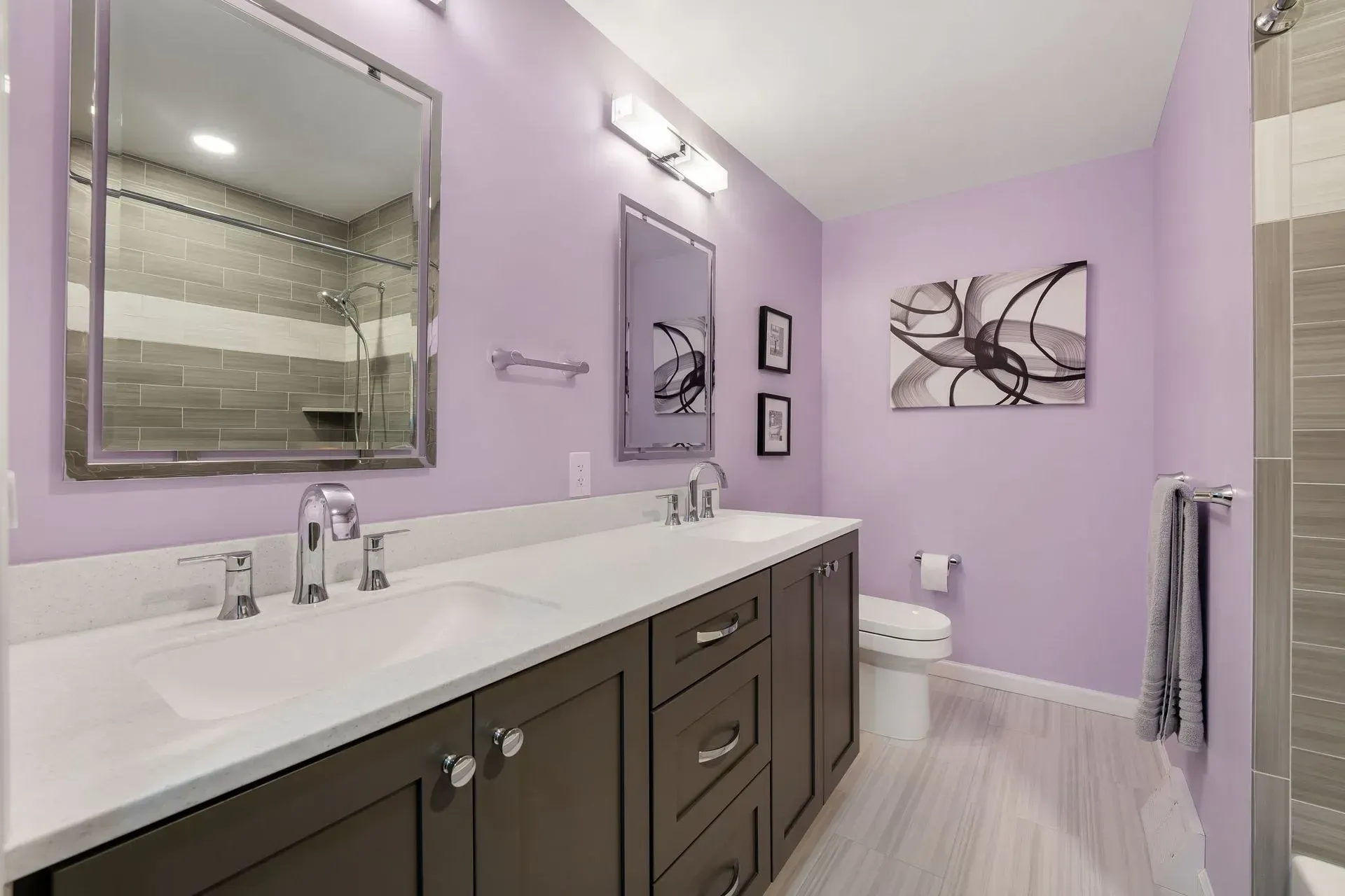 Lavender bathroom with double vanity, large mirror, and wall art In Bucks County PA