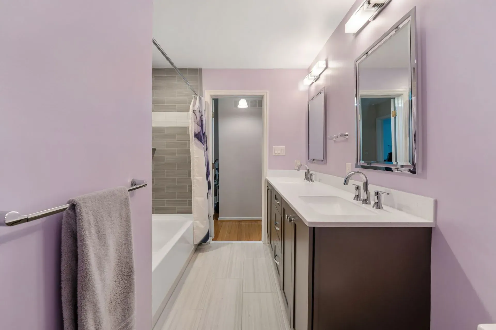 Modern bathroom with lavender walls, double vanity, large mirror, and shower stall In Bucks County PA