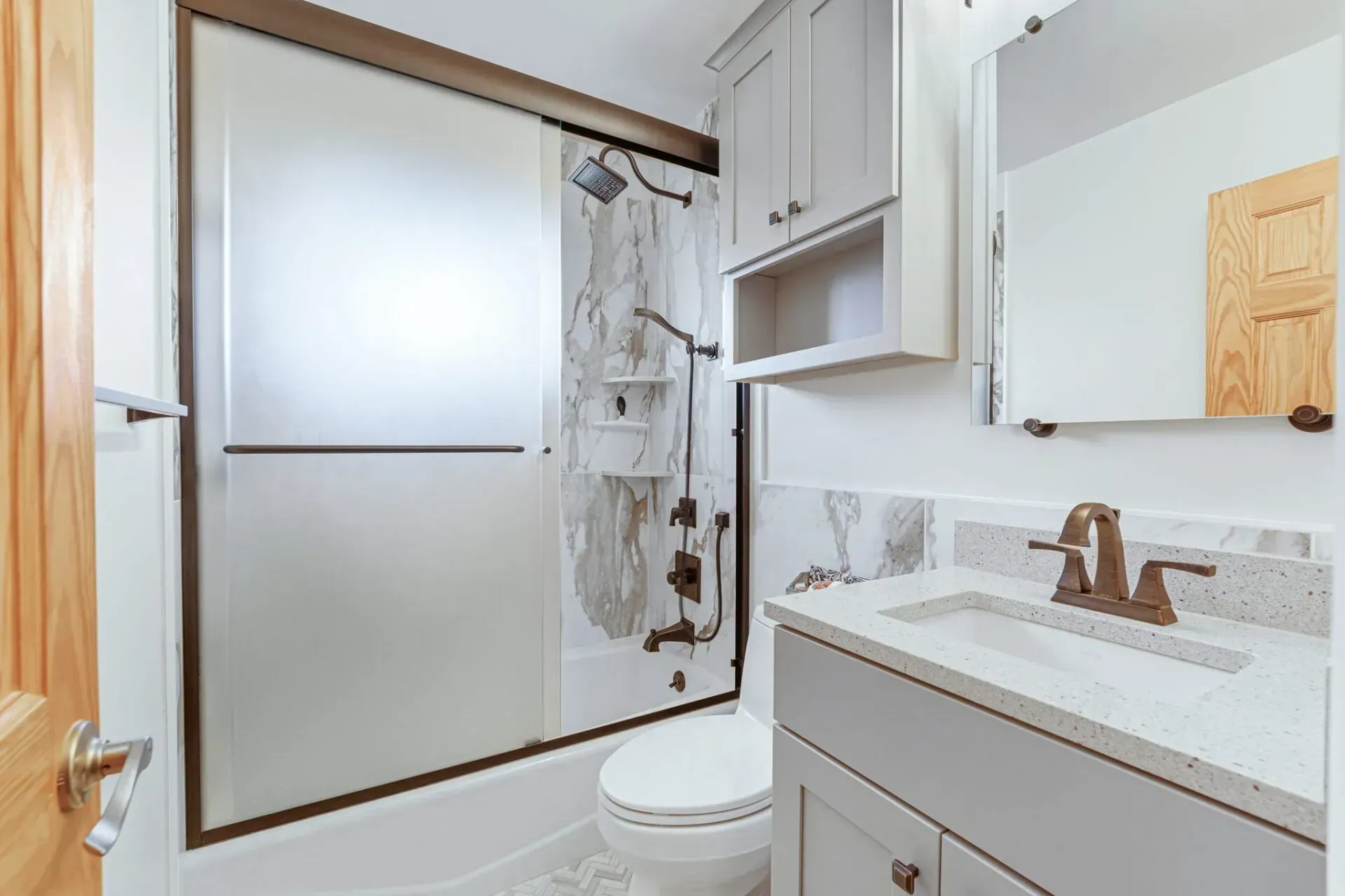 Modern bathroom with frosted shower, white vanity, toilet, and wood accents In Bucks County PA