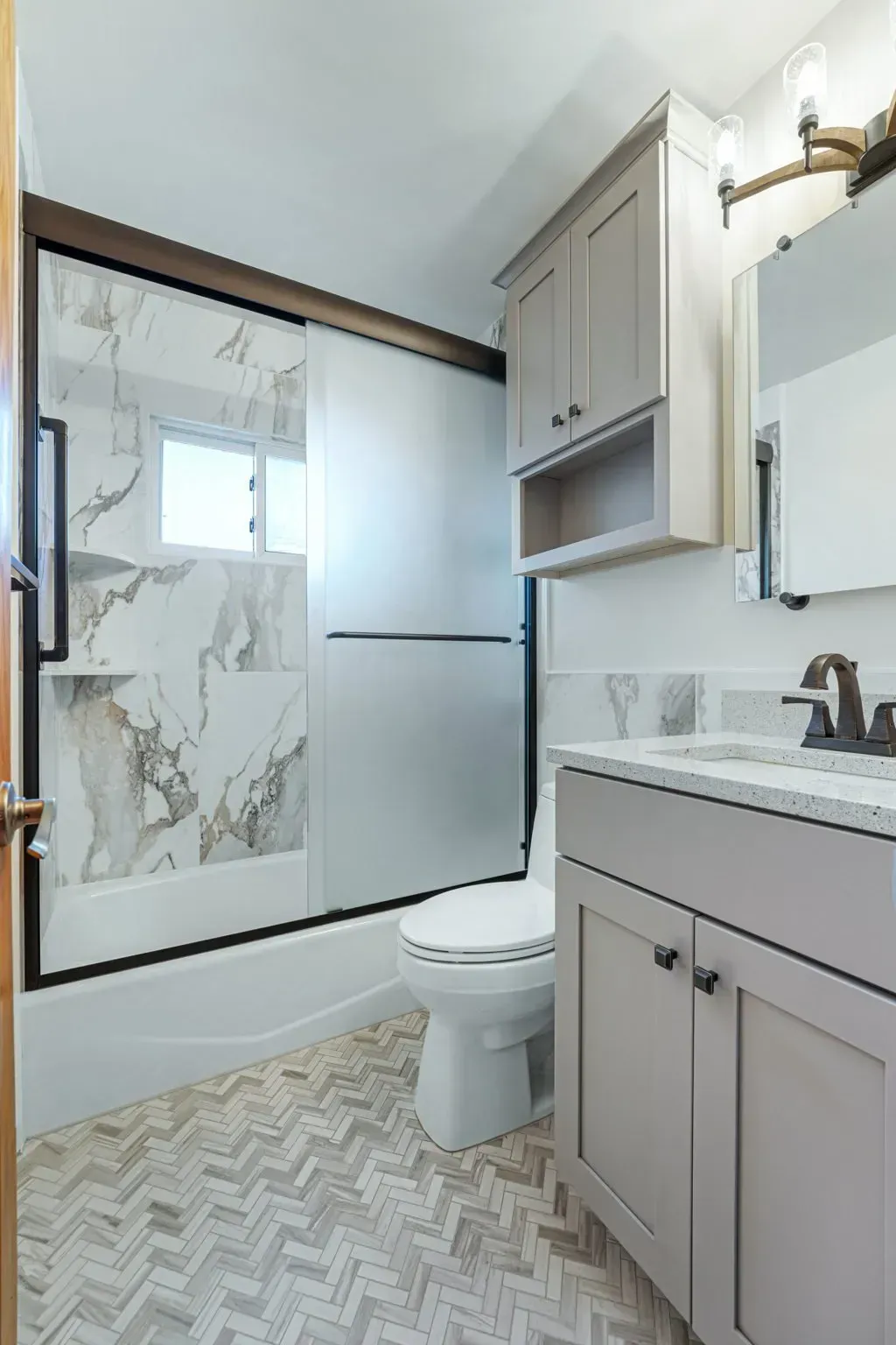 Modern bathroom with glass shower, gray vanity, and patterned floor tile In Bucks County PA